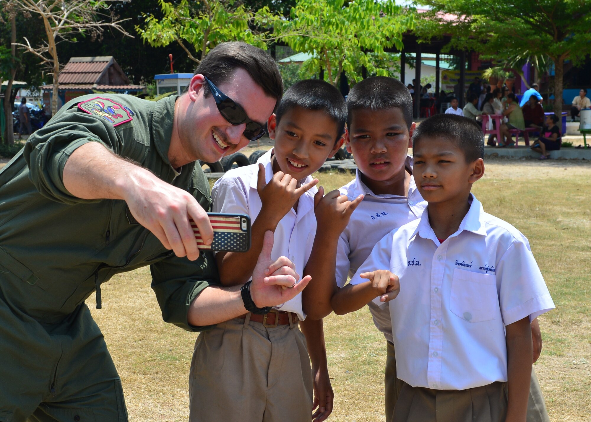 Capt. Lance Coldren, a pilot from the 67th Fighter Squadron, Kadena Air Base, Japan, poses for a photo with students during the Exercise Cope Tiger 16 combined civic action engagement at Thong Chai Wittaya Primary School, Korat, Thailand, March 15, 2016. The combined civic action engagement provides an outlet for the countries participating in Cope Tiger to give back to the community surrounding Korat Royal Thai Air Force Base. Exercise Cope Tiger is multilateral field training exercise and includes more than 1,200 personnel from the United States, Thailand and Singapore. The purpose of this exercise is to improve readiness and interoperability between three countries and continue the growth of strong relationships within the Asia-Pacific Region. (U.S. Air Force Photo by Tech Sgt. Aaron Oelrich/Released)