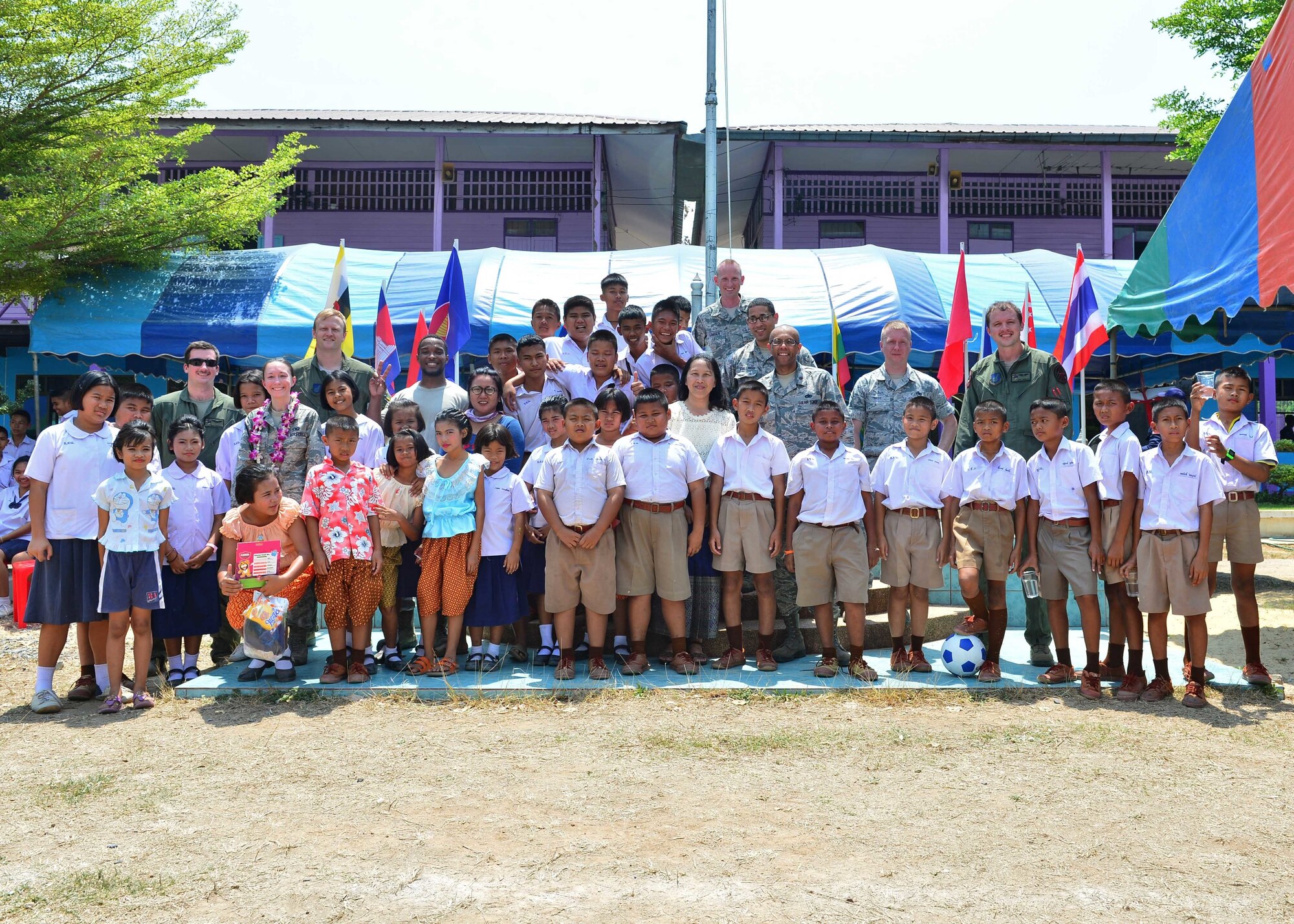 Airmen pose for a photo with students and staff members during the Exercise Cope Tiger 16 combined civic action engagement at Thong Chai Wittaya Primary School, Korat, Thailand, March 15, 2016. The combined civic action engagement provides an outlet for the countries participating in Cope Tiger to give back to the community surrounding Korat Royal Thai Air Force Base. Exercise Cope Tiger is multilateral field training exercise and includes more than 1,200 personnel from the United States, Thailand and Singapore. The purpose of this exercise is to improve readiness and interoperability between three countries and continue the growth of strong relationships within the Asia-Pacific Region. (U.S. Air Force Photo by Tech Sgt. Aaron Oelrich/Released)