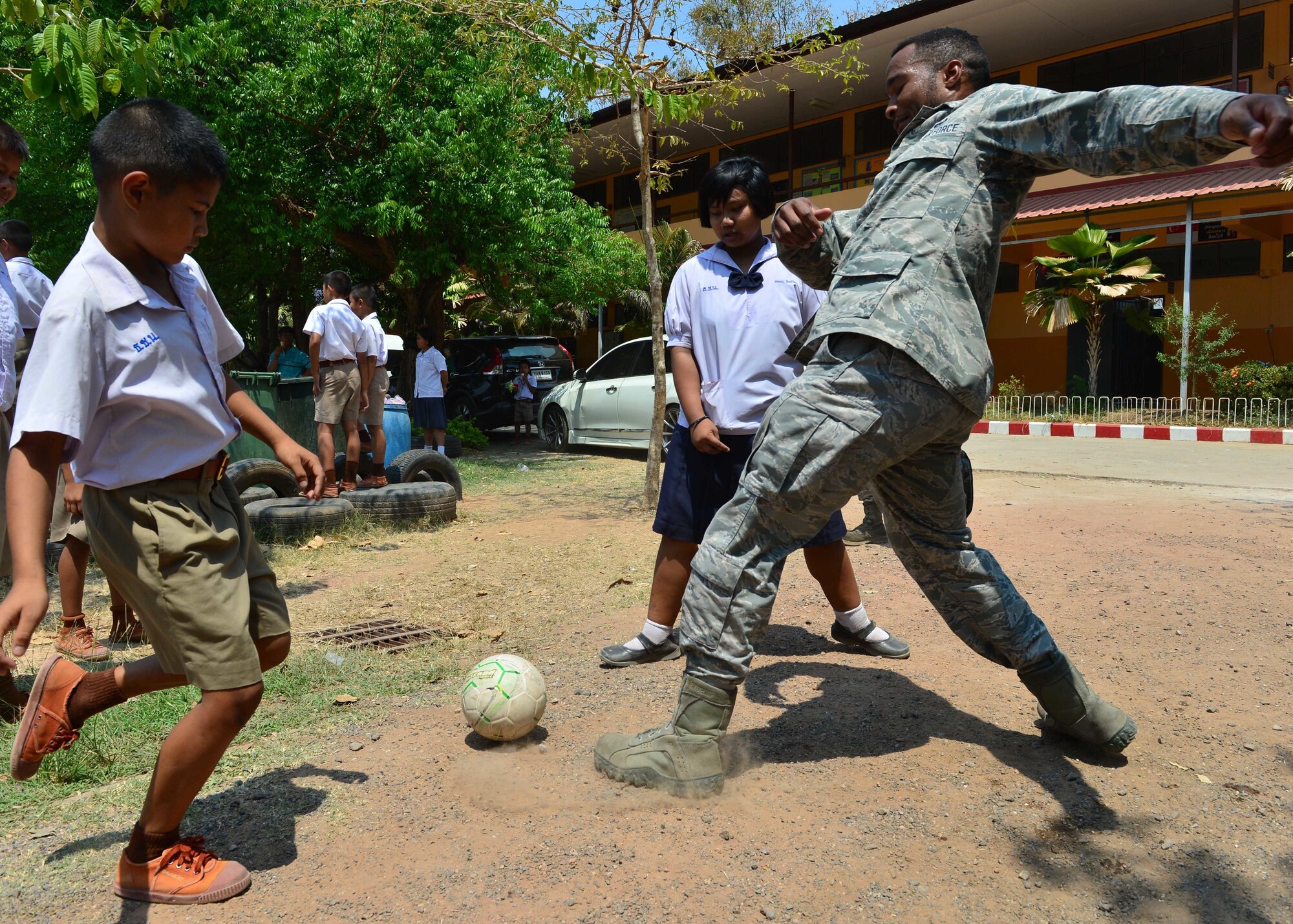 Senior Airman Joseph Anderson, from the 67th Aircraft Maintenance Squadron, Kadena Air Base, Japan, plays soccer with students during the Exercise Cope Tiger 16 combined civic action engagement at Thong Chai Wittaya Primary School, Korat, Thailand, March 15, 2016. The combined civic action engagement provides an outlet for the countries participating in Cope Tiger to give back to the community surrounding Korat Royal Thai Air Force Base. Exercise Cope Tiger is multilateral field training exercise and includes more than 1,200 personnel from the United States, Thailand and Singapore. The purpose of this exercise is to improve readiness and interoperability between three countries and continue the growth of strong relationships within the Asia-Pacific Region. (U.S. Air Force Photo by Tech Sgt. Aaron Oelrich/Released)