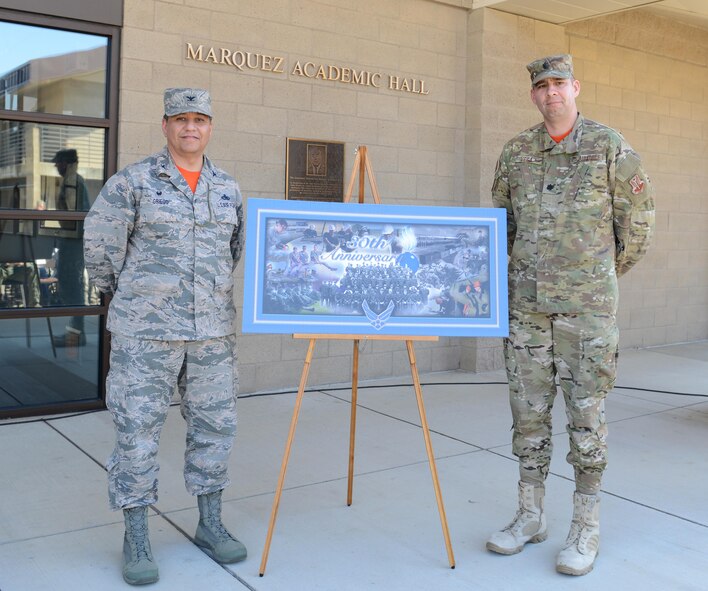 Col. Manuel Griego (left), 9th Maintenance Group commander, and Lt. Col. Frank Vega, 9th Munitions Squadron commander, reveal a commemorative poster celebrating the Air Force Combat Ammunition Center’s (AFCOMAC) 30th Anniversary March 18, 2016, at Beale Air Force Base, California. Thirty years ago, AFCOMAC was developed to provide the Air Force munitions community advanced combat training in mass munitions planning and production techniques. (U.S. Air Force photo by Senior Airman Bobby Cummings)