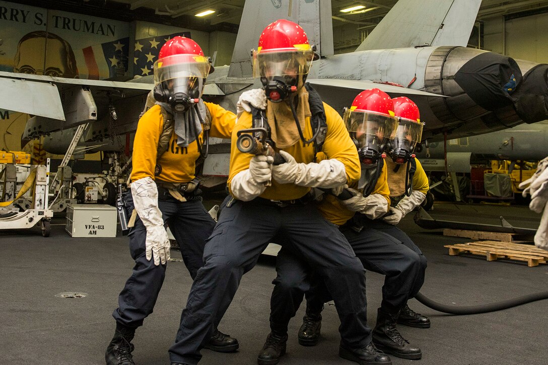 Sailors fight a simulated fire during a general quarters drill in the hangar bay of the aircraft carrier USS Harry S. Truman in the Arabian Gulf, March 14, 2016. The Truman Carrier Strike Group is deployed in support of Operation Inherent Resolve and other security efforts in the U.S. 5th Fleet area of responsibility. Navy photo by Petty Officer Seaman A.O. Tinubu