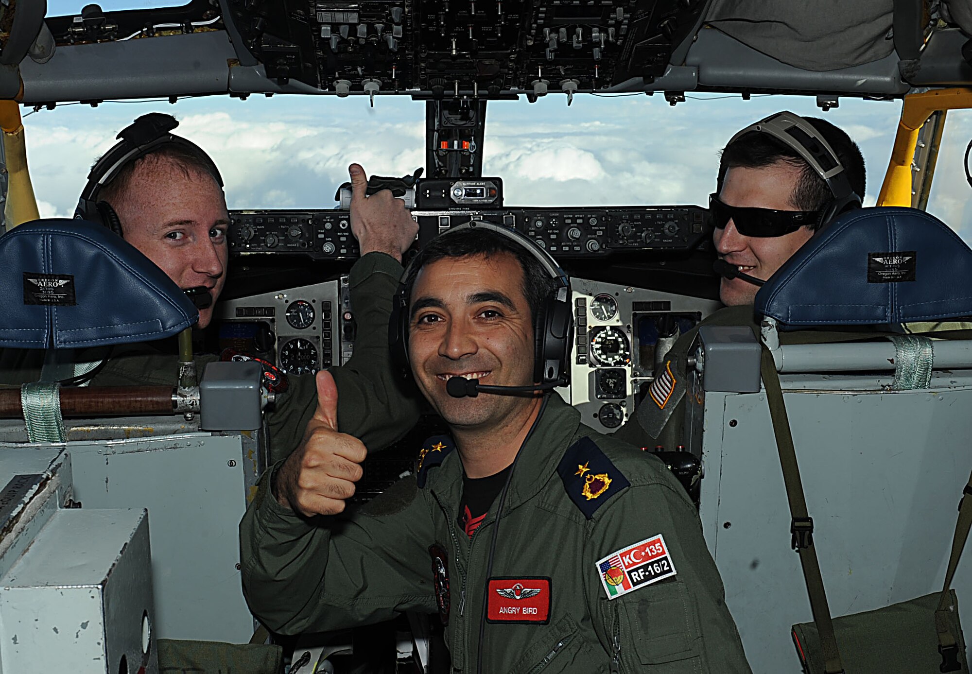 U.S. Capt. Alex Durstein (left), 344th Air Refueling Squadron pilot, Turkish air force Maj. Orcun Kus(center), 101st ARS commander and U.S. 1st Lt. Nate Foltz, 344th ARS pilot, pose for a photo, March 8, 2016, over Nevada. The U.S. and Turkish air force crews flew the first-ever KC-135 Stratotanker formation flights during Red Flag 16-2. Red Flag involves a variety of fighter, bomber, reconnaissance and air lift support aircraft that require mid-air tanker support during the exercise. (U.S. Air Force photo/Senior Airman David Bernal Del Agua)