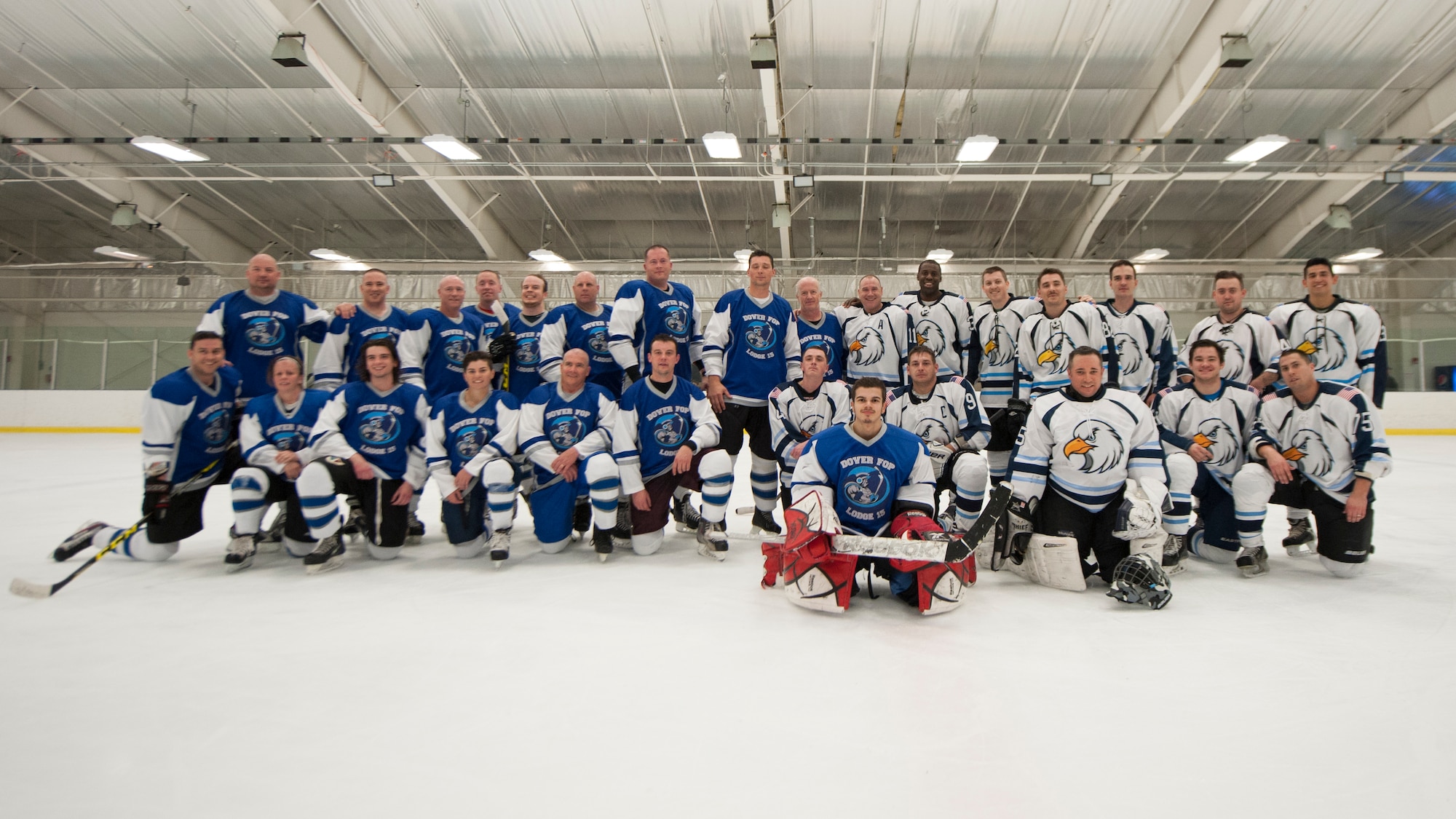 The Dover Eagles and Fraternal Order of Police Lodge 15 hockey teams pose for a group photo after a charity hockey game March 13, 2016, at the Centre Ice Rink in Harrington, Del. This charity game raised money for the Concerns of Police Survivors (COPS) charity. (U.S. Air Force photo/Senior Airman Zachary Cacicia)