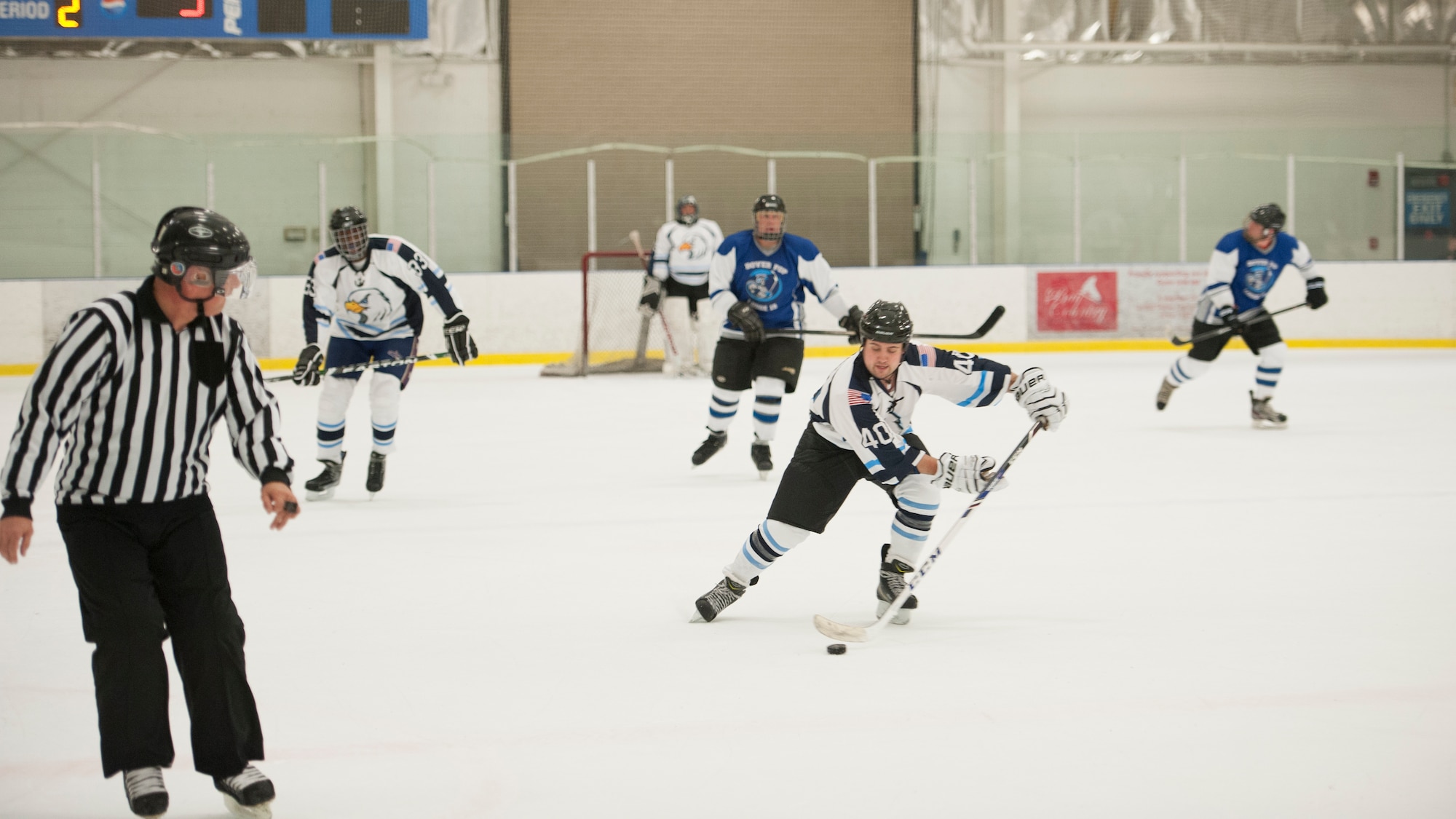 Nicolas Stewart, Dover Eagles defenseman, takes the puck down the ice during a charity hockey game March 13, 2016, at the Centre Ice Rink in Harrington, Del. The Eagles are comprised of Team Dover Airmen, family members and civilian employees. (U.S. Air Force photo/Senior Airman Zachary Cacicia)
