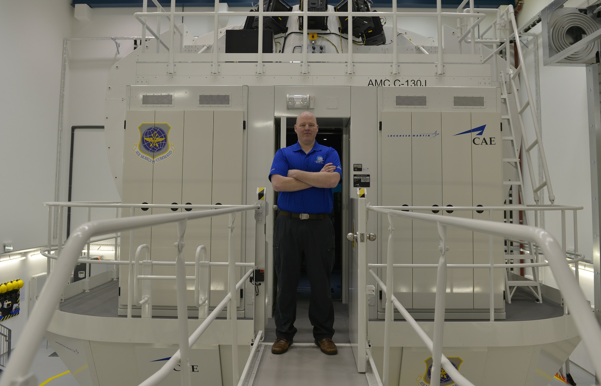 Brandon Cowell, 86th Operations Support Squadron C-130J Super Hercules simulator site manager and pilot, stands in front of the simulator March 16, 2016, at Ramstein Air Base, Germany. His job is to work with instructors to help them train pilots that need to retrain. (U.S. Air force photo/Airman 1st Class Lane T. Plummer)