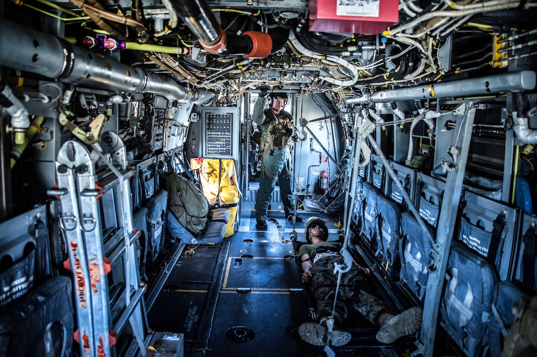 Marine Corps Cpl. Austin Meekins, standing, waits inside an MV-22 Osprey aircraft to transport a simulated casualty during a casualty evacuation exercise at landing zone Penguin on Camp Lejeune, N.C., March 10, 2016. Meekins is a crew chief assigned to Marine Tiltrotor Squadron 365. Marine Corps photo by Lance Cpl. Erick Galera