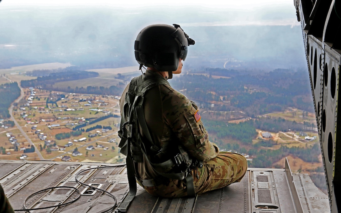 An Army crew chief sits on the tailgate of his CH-47 Chinook helicopter and looks over the Sicily drop zone as part of a reenlistment jump on Fort Bragg, N.C., March 11, 2016. The crew chief is assigned to the 82nd Combat Aviation Brigade. Army photo by Capt. Joe Bush