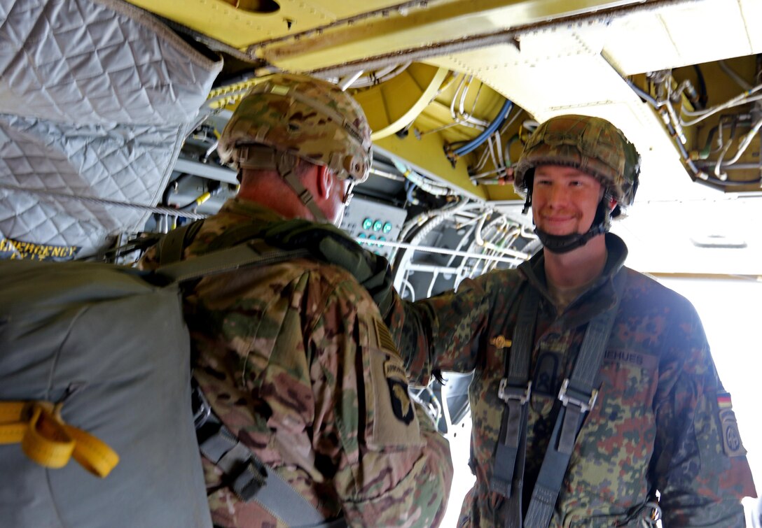 A German jump master, right, smiles before U.S. Army Brig. Gen. Brian Winski, center, deputy commander, 82nd Airborne Division, leads paratroopers out of a CH-47 Chinook helicopter above Sicily drop zone on Fort Bragg, N.C., March 11, 2016. 