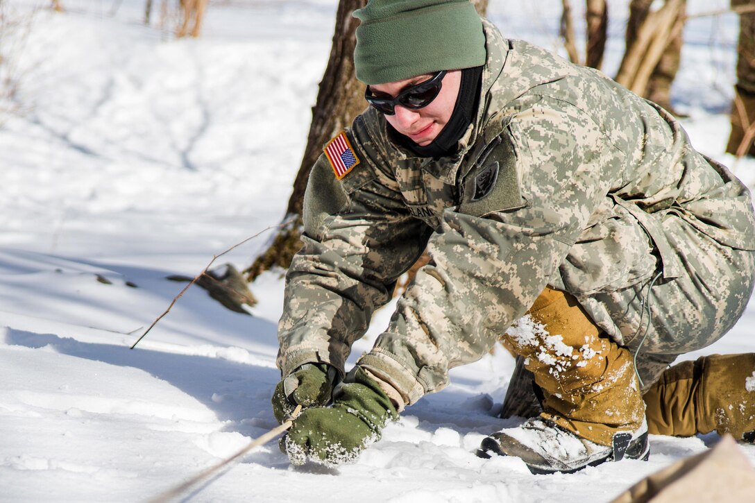 Army Spc. Mitchell Delancey sets a tent line for a bivouac site at Smuggler's Notch, Jeffersonville, Vt., March 5, 2016. Delancey is assigned to Company A, 3rd Battalion, 172nd Infantry Regiment, 86th Infantry Brigade Combat Team, Mountain. Vermont Army National Guard photo by Staff Sgt. Chelsea Clark