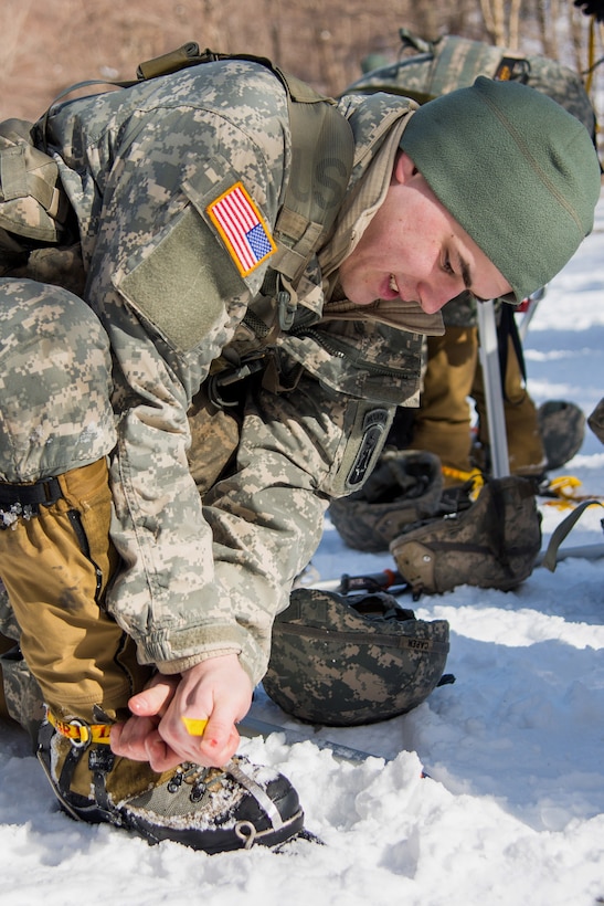 Army Spc. Jeremy Breckenridge tightens his crampons while prepping for vertical ice climbing at Smuggler's Notch, Jeffersonville, Vt., March 5, 2016. Breckenridge is an infantryman assigned to Company A, 3rd Battalion, 172nd Infantry Regiment, 86th Infantry Brigade Combat Team, Mountain. Vermont Army National Guard photo by Staff Sgt. Chelsea Clark