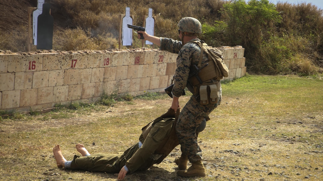 Cpl. Bradley Saunders, an infantry assaultman with Fox Company, 2nd Battalion, 3rd Marine Regiment, and a Platteville, Wis., native, drags a training dummy while shooting targets with his M9 Service Pistol during a Pacific Combat Shooting Match at the Kaneohe Bay Range Training Facility at Marine Corps Base Hawaii, March 16, 2016. Teams from different units used various weapons and tactics to achieve the fastest time possible on different courses of fire, while earning points for awards during the competition. Marines from the Marine Corps Combat Shooting Team instructed and gave advice to the Marines participating in the event. (U.S. Marine Corps Photo by Lance Cpl. Jesus Sepulveda Torres)