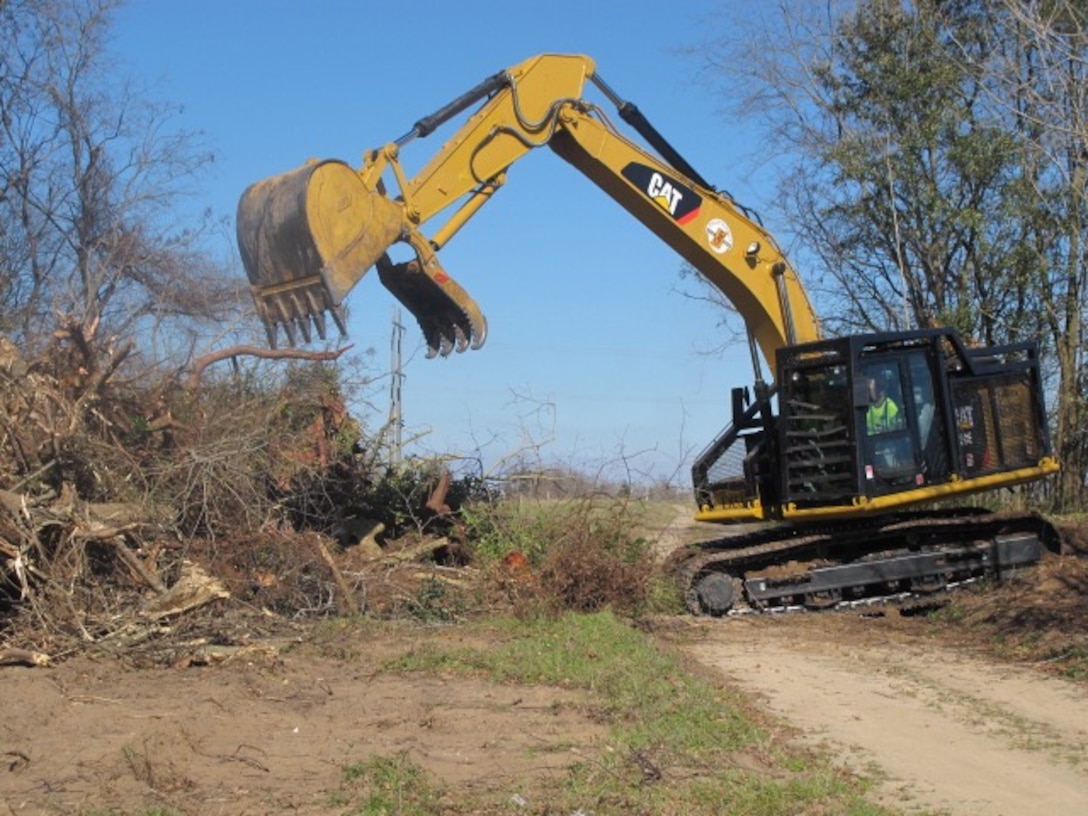 A backhoe removes trees and debris from one of two sites that will house the dissolved oxygen system on the Savannah River.