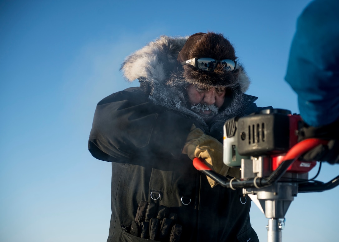 Hector Castillo, left, with Arctic Submarine Lab, and Navy Lt. Mitchell Nelson drill a hole in the Arctic ice to begin testing the water's temperature and salinity during Ice Exercise 2016 at Ice Camp Sargo, Arctic Circle, March 9, 2016. Navy photo by Petty Officer 2nd Class Tyler N. Thompson