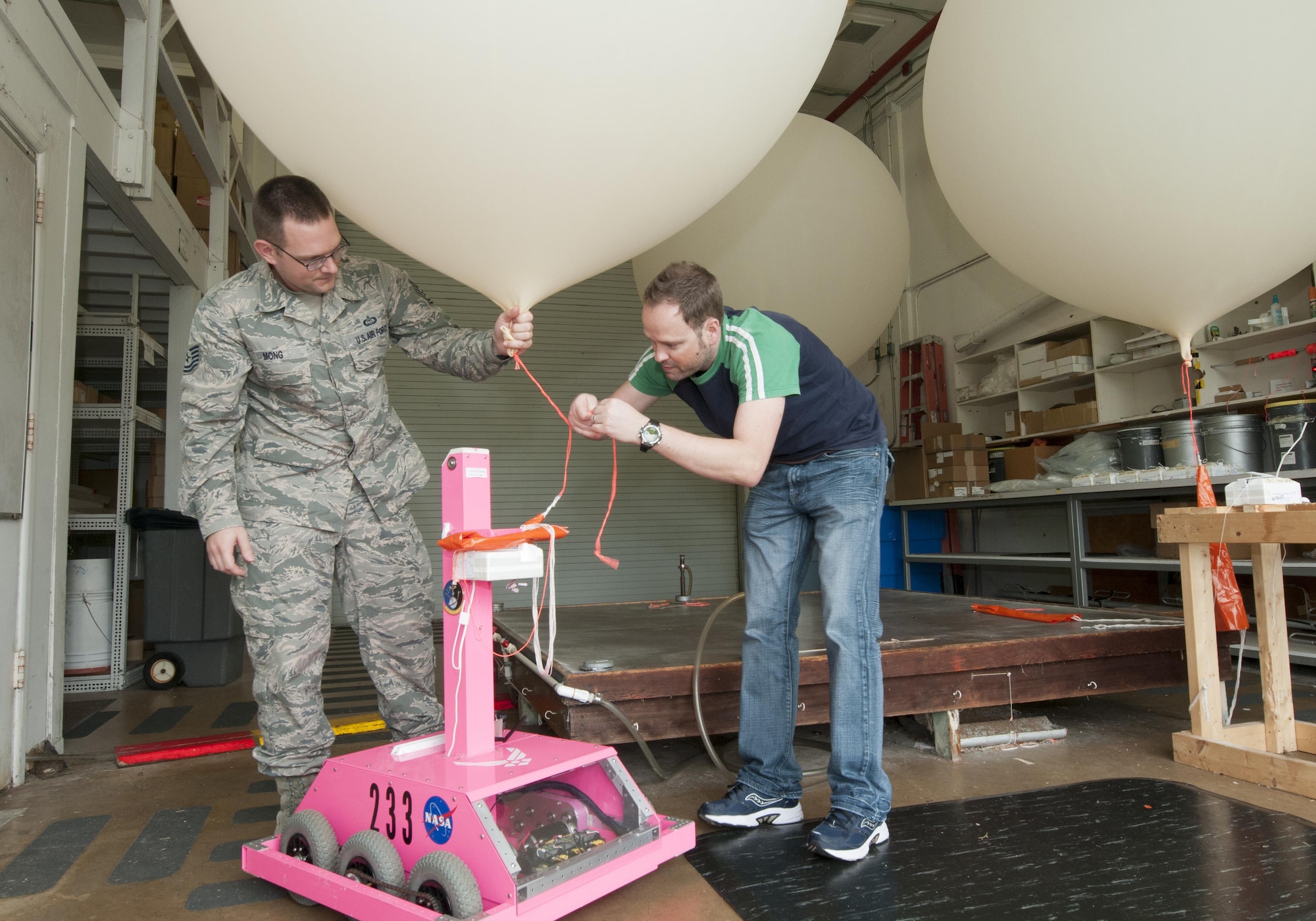 Tech Sgt. Matthew Mong, a 45th Weather Squadron range weather forecaster, and Mike Boyer, a meteorological data specialist, attach a weather balloon to a “weatherbot” inside the weather balloon facility on Cape Canaveral Air Force Station, Fla., Feb. 24, 2016. The remote-controlled robot releases balloons when lightning is present so forecasters can stay safely indoors. Data from the balloons, particularly wind speed and direction, help Airmen and mission partners decide either to launch or postpone a space mission. (U.S. Air Force photo/Sean Kimmons)