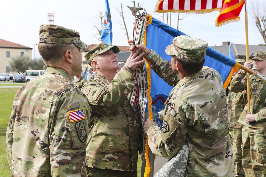 Maj. Gen. George Franz III, commanding general of Intelligence and Security Command, observes as Col. Timothy Higgins, 207th Military Intelligence Brigade commander, and his senior enlisted leader, Command Sgt. Maj. Kenneth Segraves, unfurl the campaign streamers on a new unit guidon during the activation ceremony of 207th MI Bde. March 16, 2016 here at Hoekstra Field at Caserma Ederle. The 207th MI Bde. will serve as the Theater Intelligence Brigade for U.S. Africa Command and is under operational control of U.S. Army Africa. The brigade includes the 207th MI Bde. Headquarters and 307th MI Battalion located here, as well as the 522nd MI Battalion located at Wiesbaden, Germany and the 337th MI Battalion located at Fort Sheridan, Ill. (U.S. Army Africa photo by Staff Sgt. Lance Pounds)