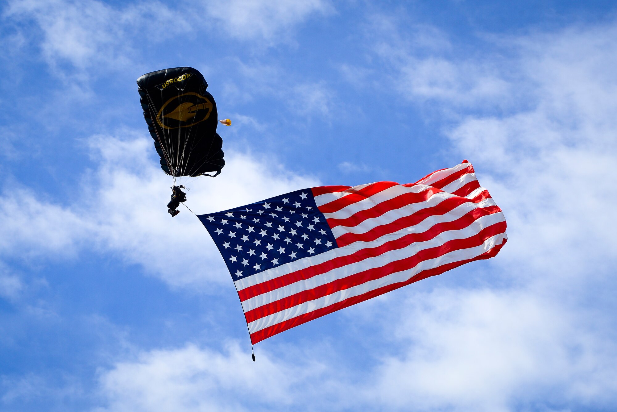 A member of the United States Special Operations Command (USSOCOM) Parachute Team displays the flag during the National Anthem during Tampa Bay AirFest 2016 at MacDill Air Force Base, Fla., March 20, 2016. The Para-Commandos perform precision freefall parachute demonstrations across the United States, informing the public about the USSOCOM mission. (U.S. Air Force photo by Staff Sgt. Melanie Hutto)     