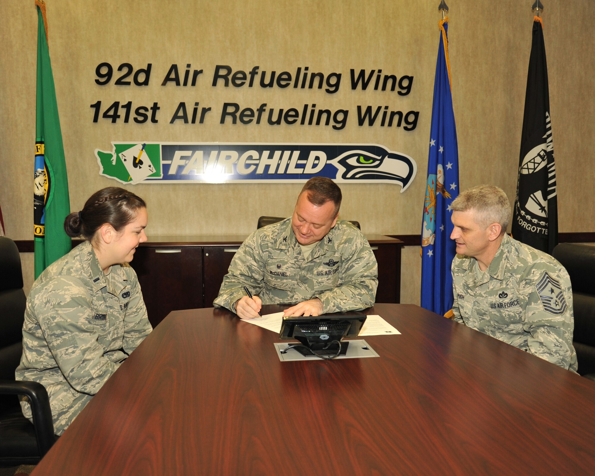 Col. Brian McDaniel, 92nd Air Refueling Wing commander, signs a donation symbolizing the beginning of the Air Force Assistance Fund as 1st Lt. Samantha Bryan 92nd Logistics Readiness Squadron fuels management officer in charge and Chief Master Sgt. Christian Pugh, 92nd ARW command chief, look on Mar. 21, 2016 at Fairchild Air Force Base, Wash. The AFAF is an annual effort to raise funds for the charitable affiliates that provide support to Air Force families in need. (U.S. Air Force photo/Staff Sgt. Samantha Krolikowski)