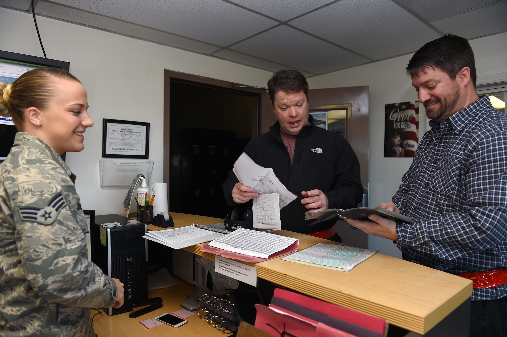 Senior Airman Jenna Kraus (left), 62nd Aerial Port Squadron ramp services journeyman, talks to Brandon Mudery (center) and Jason Aven, 62nd APS ramp services in the 62nd APS ramp services section March 17, 2016, at Joint Base Lewis-McChord, Wash. The 62nd APS, formerly known as the 62nd Air Terminal Squadron, supported the scientific stations in the Arctic Ocean by airdropping supplies on drifting ice in 1962 and continues to support worldwide airlift by enabling air transportation. (U.S. Air Force photo/Staff Sgt. Naomi Shipley)