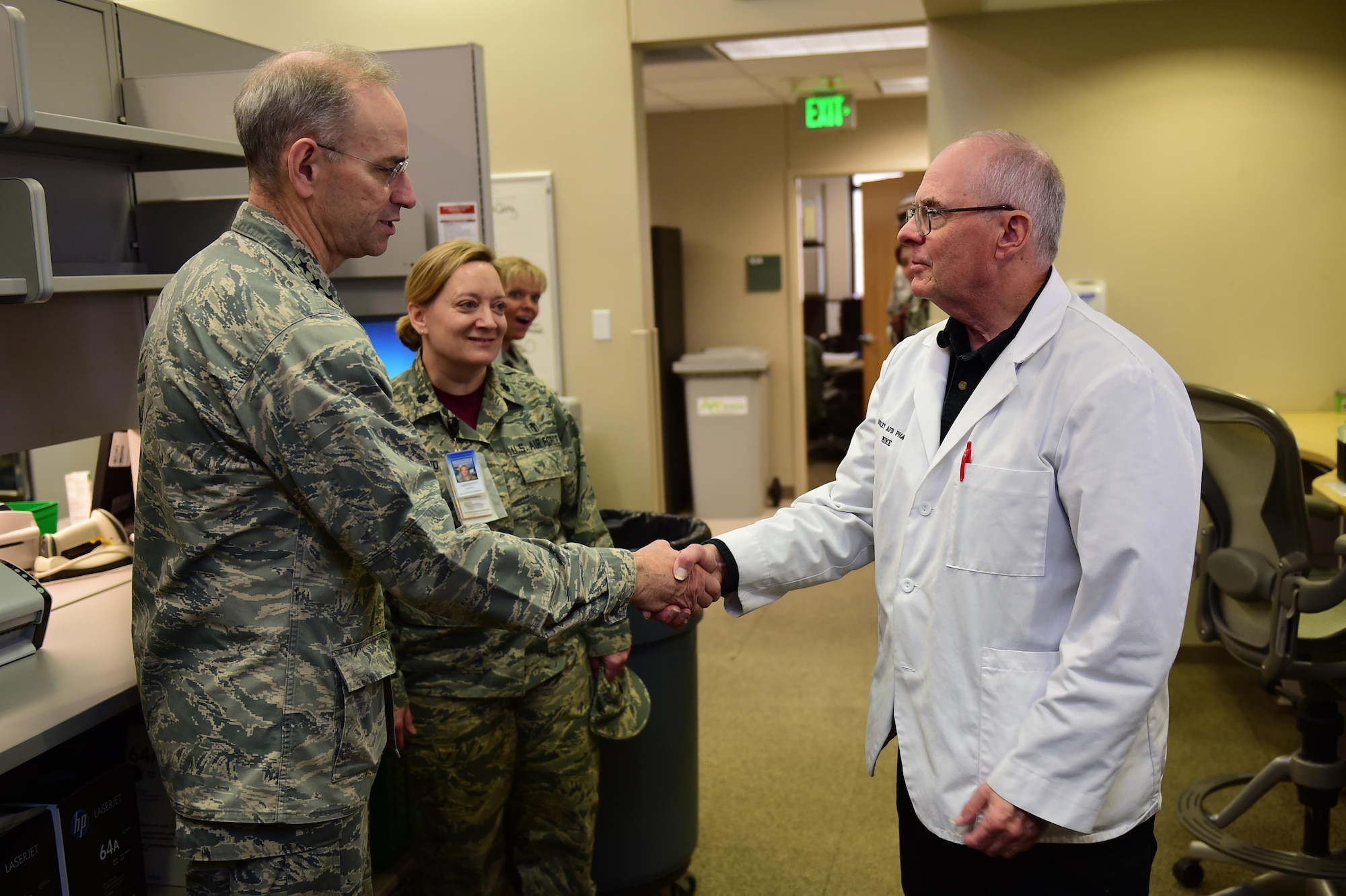 Lt. Gen. (Dr.) Mark A. Ediger, Surgeon General of the Air Force, coins Michael Buhnerkempe, longtime Buckley pharmacy technician, March 18, 2016, at the Buckley Air Force Base Pharmacy, Colo. Buhnerkempe, a veteran, has worked at the Buckley pharmacy for almost 11 years, continuing his service from the Vietnam War as a pharmacist. (U.S. Air Force photo by Airman 1st Class Gabrielle Spradling/Released)