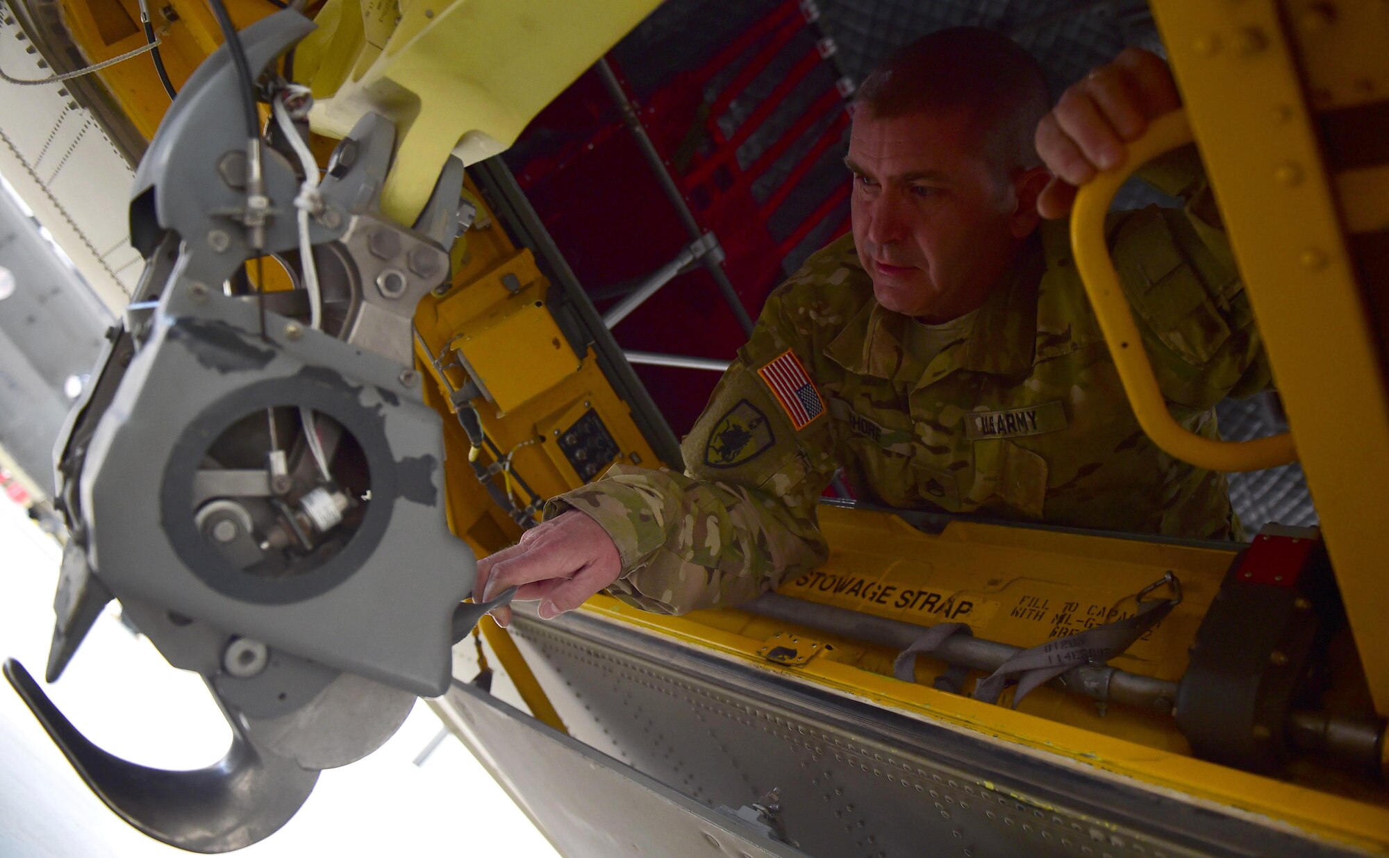 U.S. Army Staff Sgt. Wade Shore, Colorado Army National Guard CH-47 crew chief, demonstrates how the sling load hook moves in a helicopter March 3, 2016, at the Army Aviation Support Facility on Buckley Air Force Base, Colo. While in flight, the Chinook crew chief, utilizes the sling load hook to maneuver the helicopter’s load. (U.S. Air Force photo by Airman 1st Class Gabrielle Spradling/Released)