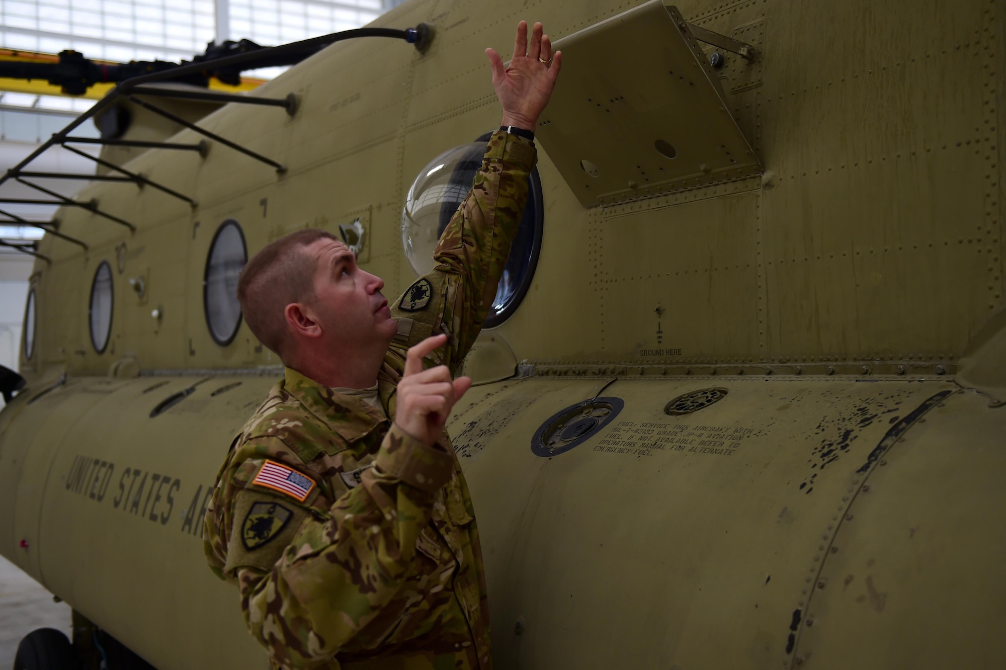 U.S. Army Staff Sgt. Wade Shore, Colorado Army National Guard CH-47 crew chief, inspects a panel on a CH-47 helicopter at the Army Aviation Support Facility on Buckley Air Force Base, Colo., March 3, 2016. A Boeing Ch-47 Chinook has many components on the outside that the crew chief is responsible for. (U.S. Air Force photo by Airman 1st Class Gabrielle Spradling/Released)