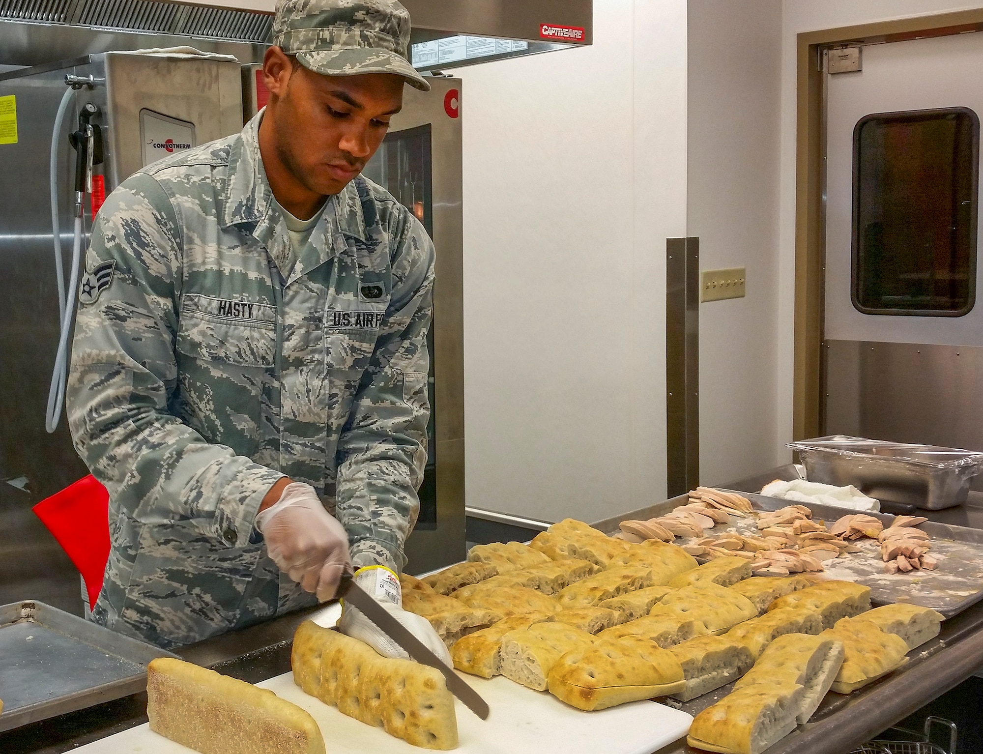 Senior Airman Roderick Hasty, 96th Force Support Squadron, slices bread for panini sandwiches, for the Breeze Dining Facility’s U-Food Grill healthy alternative line.  Hasty was one of approximately 35 Airmen who graduated from the Food Transformation Initiative training program at the Breeze March 18.  FTI promotes healthy eating in the military.  (U.S. Air Force photo/Kevin Gaddie)