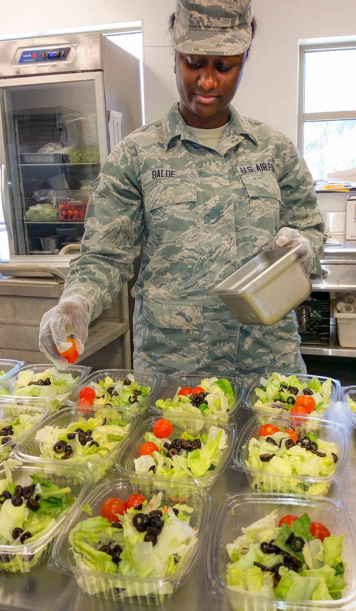 Senior Airman Aissata Balde, 96th Force Support Squadron, places tomatoes on to-go salads at the Breeze Dining Facility.  Balde was one of approximately 35 Airmen who graduated from the Food Transformation Initiative training program at the Breeze March 18.  FTI promotes healthy eating in the military.  The Breeze reopens March 24.  (U.S. Air Force photo/Kevin Gaddie)
