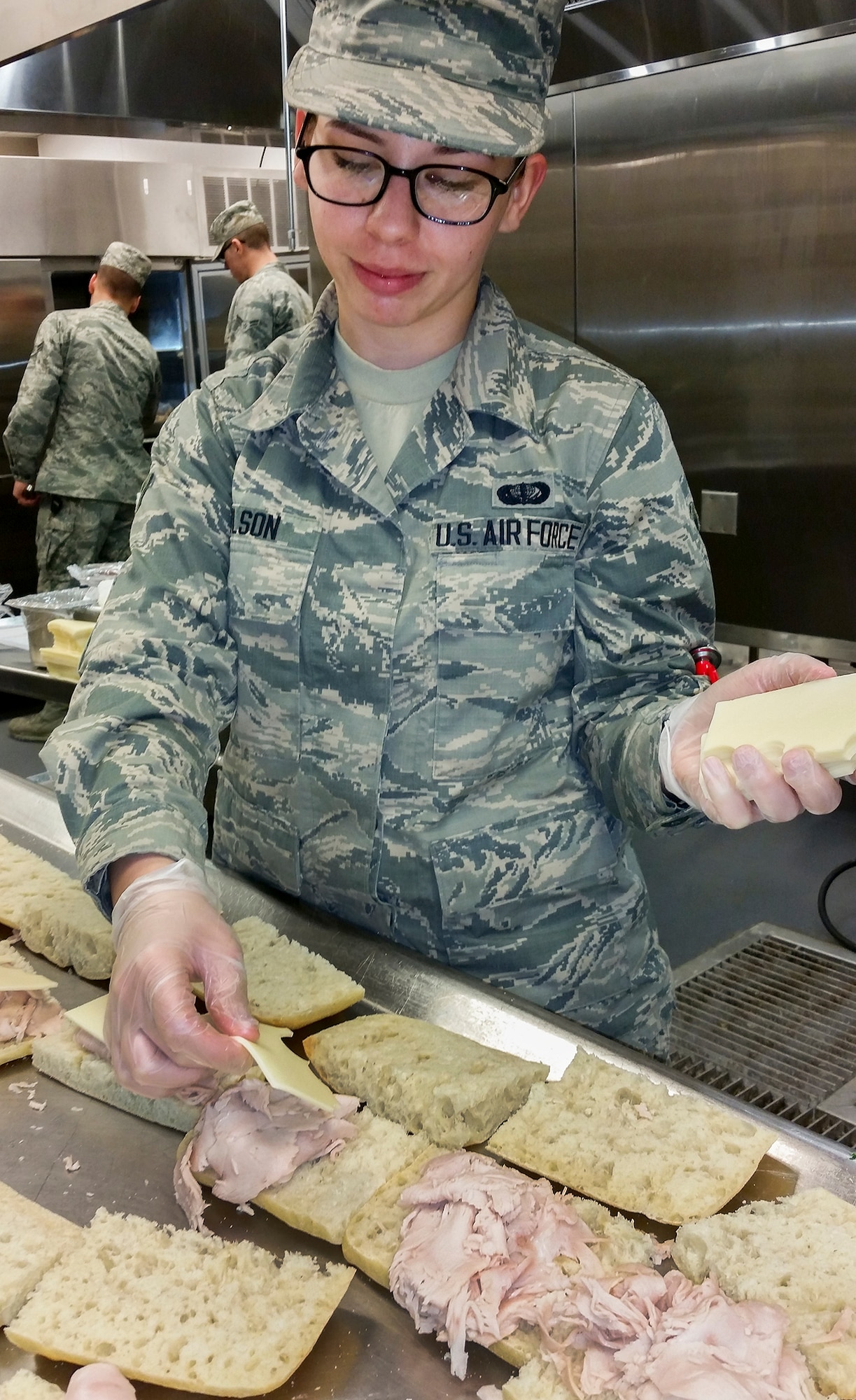 Airman Karli Wilson, 96th Force Support Squadron, lays sliced cheese on panini sandwiches, for the Breeze Dining Facility’s U-Food Grill healthy alternative line.   Wilson was one of approximately 35 Airmen who graduated from the Food Transformation Initiative training program at the Breeze March 18.  FTI promotes healthier eating in the military.  (U.S. Air Force photo/Kevin Gaddie)