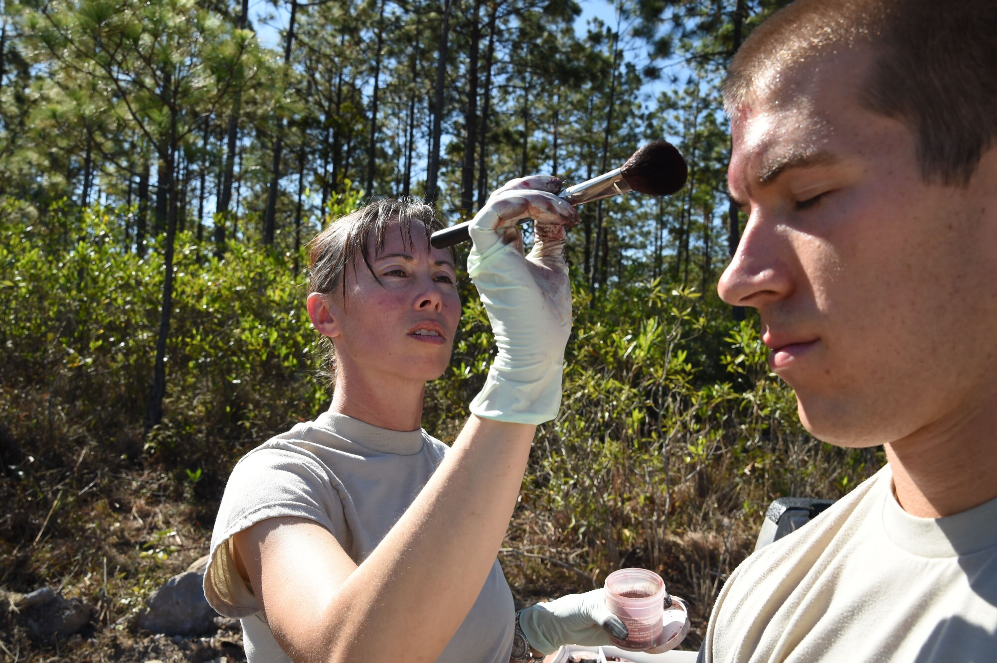 Staff Sgt. Yanna Ramaekers (left), Joint Task Force-Bravo Medical Element medic, applies simulated wounds, or moulage, on 1Lt. Andrew Lankow, Joint Task Force-Bravo Ports and Plans officer in charge, March 10, 2016 near Soto Cano Air Base, Honduras, for a simulated personnel recovery exercise. 1Lt. Lankow played a UH-60 Black Hawk helicopter crash victim for this exercise which involved both Honduran forces and Servicemembers from JTF-Bravo. (U.S. Army photo by Martin Chahin/Released)