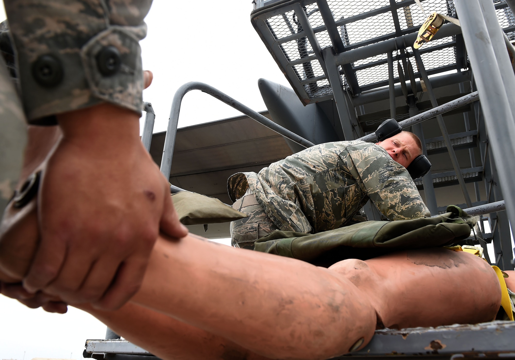 Airman 1st Class Garrett Teegestrom, 5th Expeditionary Aircraft Maintenance Squadron C-17 instruments and flight control systems technician, tends to a mock casualty during a fall protection exercise on the flightline at an undisclosed location in Southwest Asia, March 14, 2016. A fall protection plan is required at any work site where there is a potential for a member to fall from a high elevation. (U.S. Air Force photo by Staff Sgt. Jerilyn Quintanilla)