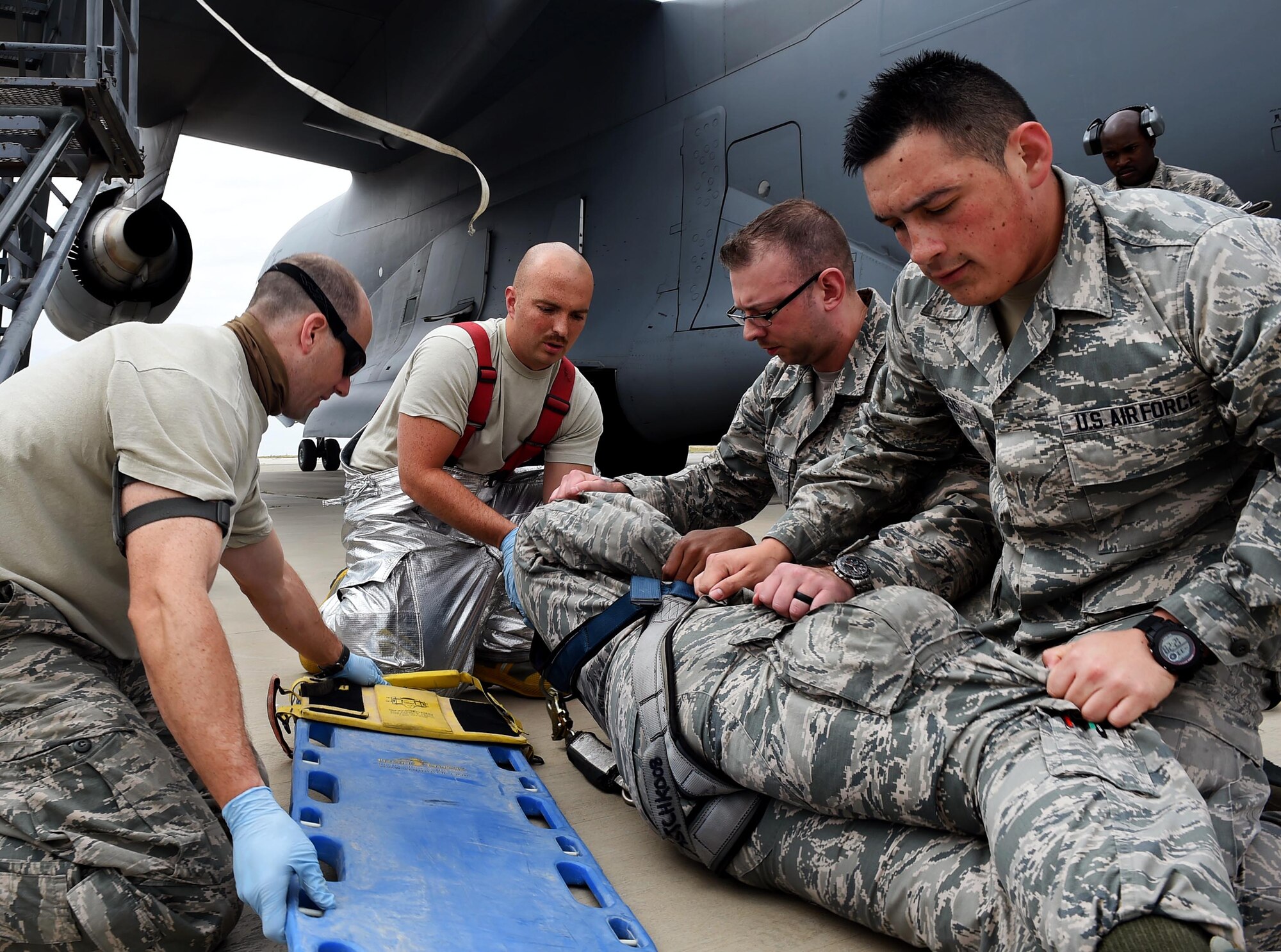 Firefighters and medics from the 386th Air Expeditionary Wing transfer a mock casualty onto a back board during a fall protection exercise on the flightline at an undisclosed location in Southwest Asia, March, 14, 2016. The purpose of the exercise was to demonstrate the ability for 5th Expeditionary Aircraft Maintenance Squadron personnel and 386th emergency responders to recover an individual who has fallen at a work site. (U.S. Air Force photo by Staff Sgt. Jerilyn Quintanilla)