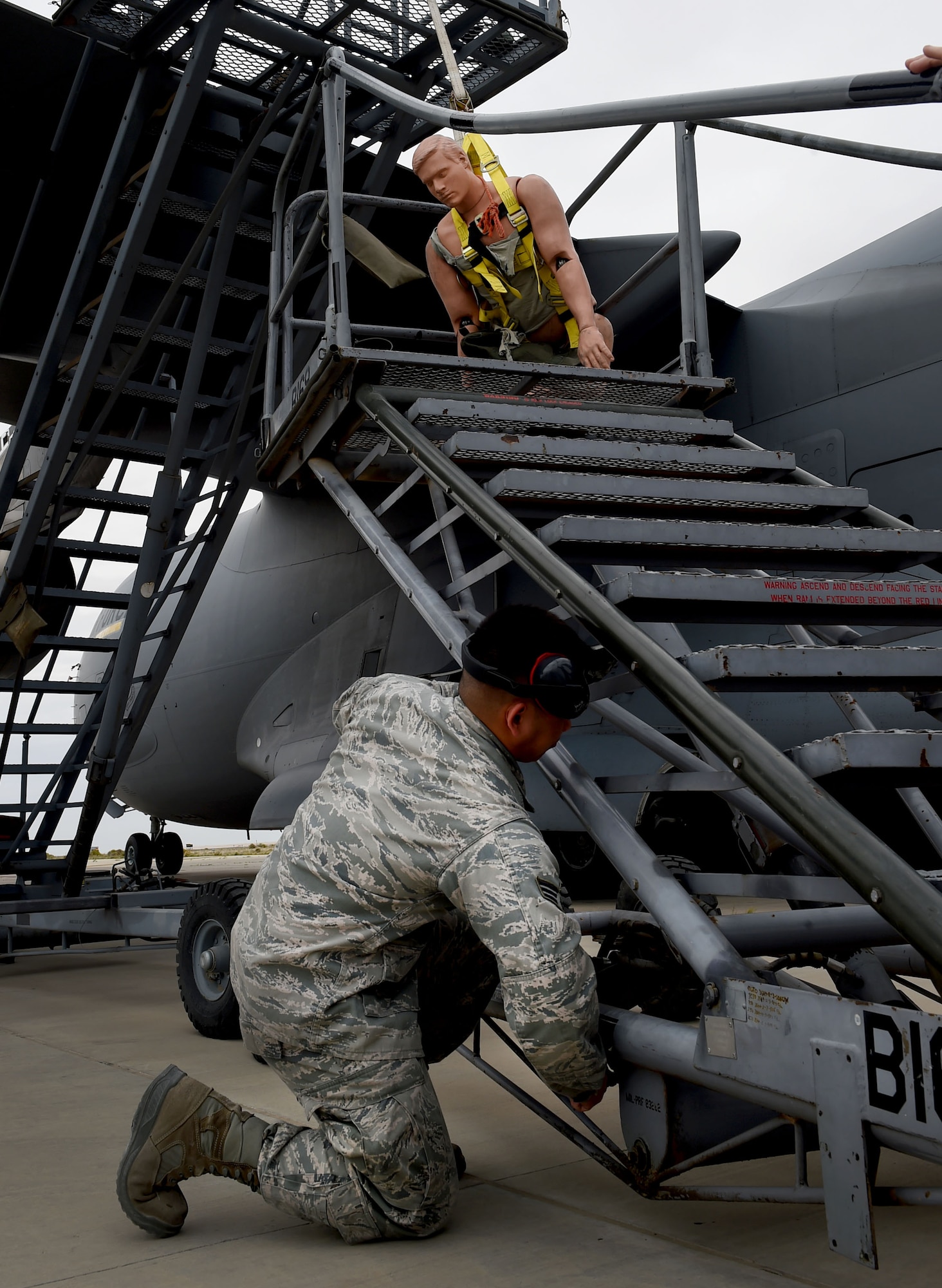 Senior Airman Jerome Llanes, 5th Expeditionary Aircraft Maintenance Squadron C-17 communications navigation systems technician, raises a B-1 stand to support a mock casualty during a fall protection exercise on the flightline at an undisclosed location in Southwest Asia, March 14, 2016. A fall protection plan is required at any work site where there is a potential for a member to fall from a high elevation. (U.S. Air Force photo by Staff Sgt. Jerilyn Quintanilla)