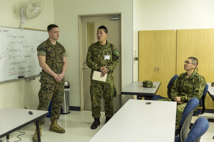 Japan Ground Self-Defense Force Sgt. Aranami, interpreter trainee, translates for Lance Cpl. Healy, left, an ordnanceman with Marine Aerial Refueler Transport Squadron 152, as he gives Marine Corps Air Station Iwakuni, Japan’s, command brief during the Public Affairs Office’s annual English seminar on Marine Corps Air Station Iwakuni, Japan, March 16, 2016. The seminar is held annually by the station Public Affairs Office to help improve upon the JGSDF’s understanding and use of the English language prior to their deployment in support of exercises in both the United States and Japan.  (U.S. Marine Corps photo by Sgt. Antonio J. Rubio/Released)