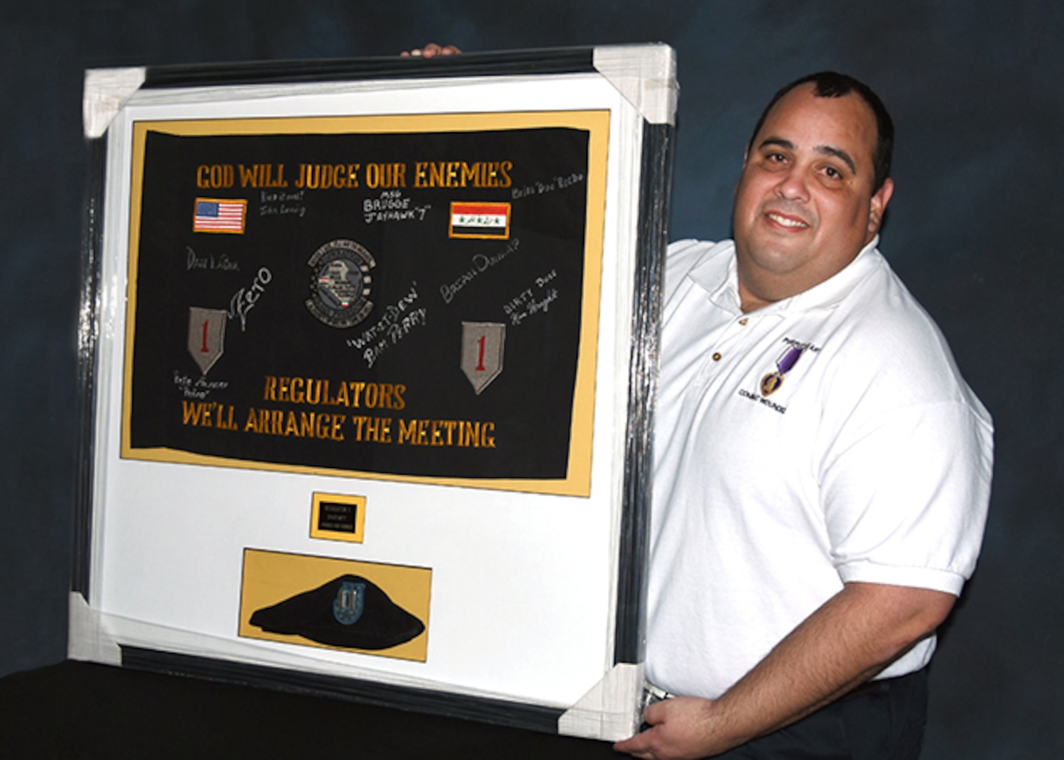 Retired Army Capt. Santiago “Angel” Rodriguez poses March 7, 2016 with his framed unit guidon and the beret he wore when injured on his last deployment as commander of the 242th Mountain Special Forces Team, 10th Group Special Operations Command. Rodriguez spoke about his experiences as a wounded warrior during the Defense Logistics Agency Aviation Senior Leader Conference, March 1 – 3, 2016 on Defense Supply Center Richmond, Virginia. Rodriguez currently serves as a customer account specialist in DLA Aviation’s Customer Operations Directorate 