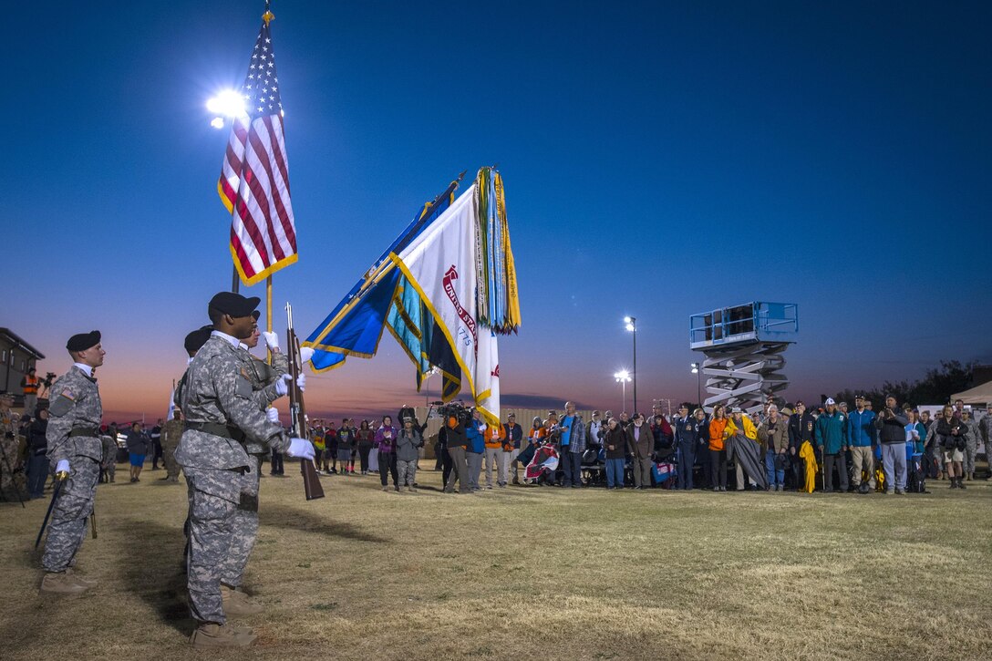 An honor guard presents the colors as the sun rises during the playing of the National anthem before the Bataan Memorial Death March at White Sands Missile Range, N.M., March 20, 2016. Survivors of the Bataan Death March are standing in the background, including retired U.S. Army Col. Ben Skardon, 98, in yellow jacket, who was the only survivor to walk in this years' memorial march. Army photo by Staff Sgt. Ken Scar