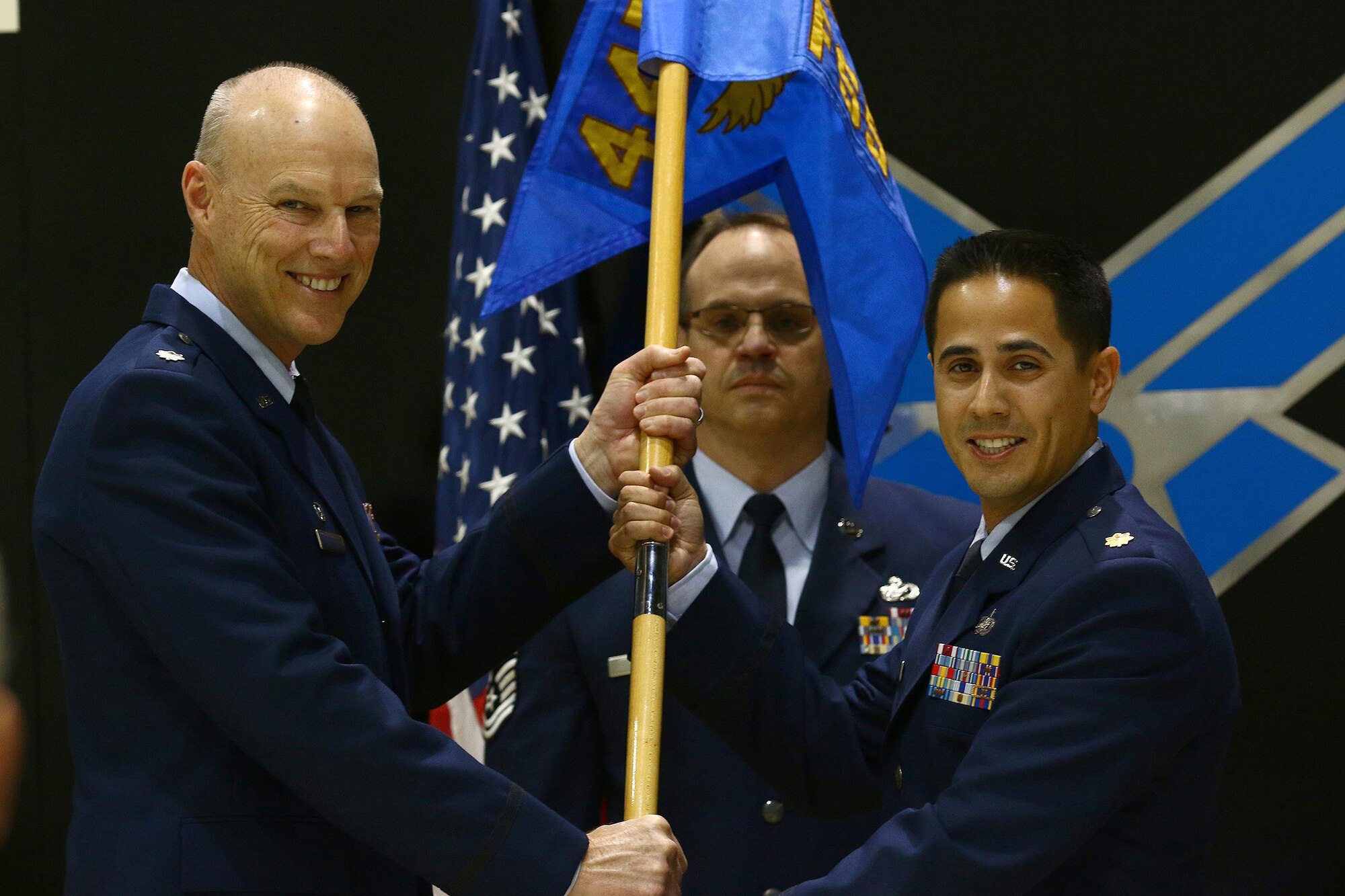Senior Master Sgt. Anthony Johns, 445th Force Support Squadron first sergeant, looks on as Lt. Col. Dale Bateman, 445th Mission Support Group commander passes the guidon to Maj. Jason Miller, incoming 445th FSS commander, during the squadron’s change of command ceremony  March 5, 2016. 