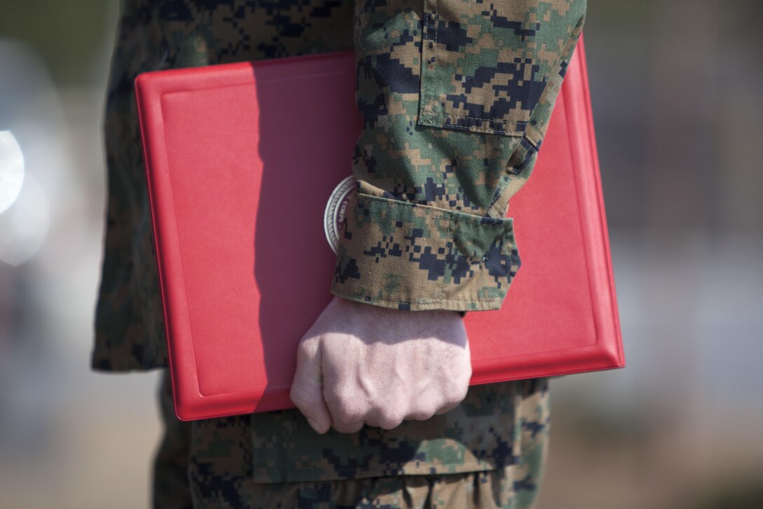 Cpl. Joseph Currey grips his award during an award ceremony at Marine Corps Air Station Cherry Point, N.C., March 1, 2016. Currey was awarded the Navy and Marine Corps Commendation Medal for his actions after witnessing an ambulance wreck. Currey demonstrated his devotion to serving others as he placed the well-being of the injured personnel above his own by running towards the scene of an accident and rendering aide to those need. Currey is an air support operations operator with Marine Aviation Support Squadron 1. (U.S. Marine Corps photo by Cpl. Austin A. Lewis, U.S. Marine Corps caption by Cpl. N.W. Huertas/Released)