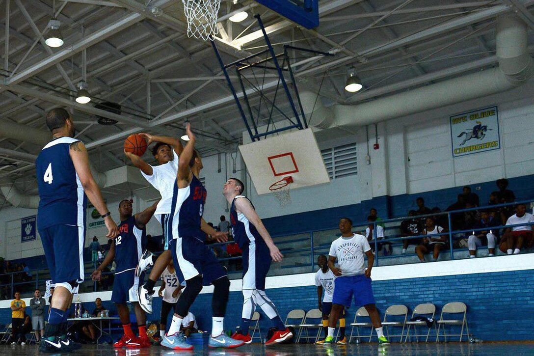 Team SJ AFB plays defense against a local community team during a basketball tournament, March 19, 2016, at Dillard Middle School in Goldsboro, North Carolina. Airmen from the base helped coordinate the tournament to build a stronger bond between the community and Team Seymour. (U.S. Air Force photo/Airman 1st Class Ashley Williamson)