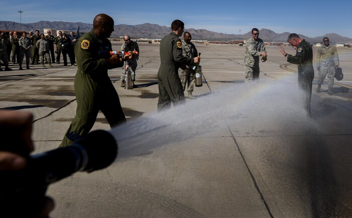 Maj. Gen.  Jay Silveria, United States Air Force Warfare Center commander, gets sprayed from a fire hose as his family and friends look on after his final flight at Nellis Air Force Base, Nev., March 10, 2016. It’s traditional for the after the pilots fini flight to be showered once he disembarks from the plane.  (U.S. Air Force photo by Airman 1st Class Kevin Tanenbaum) 