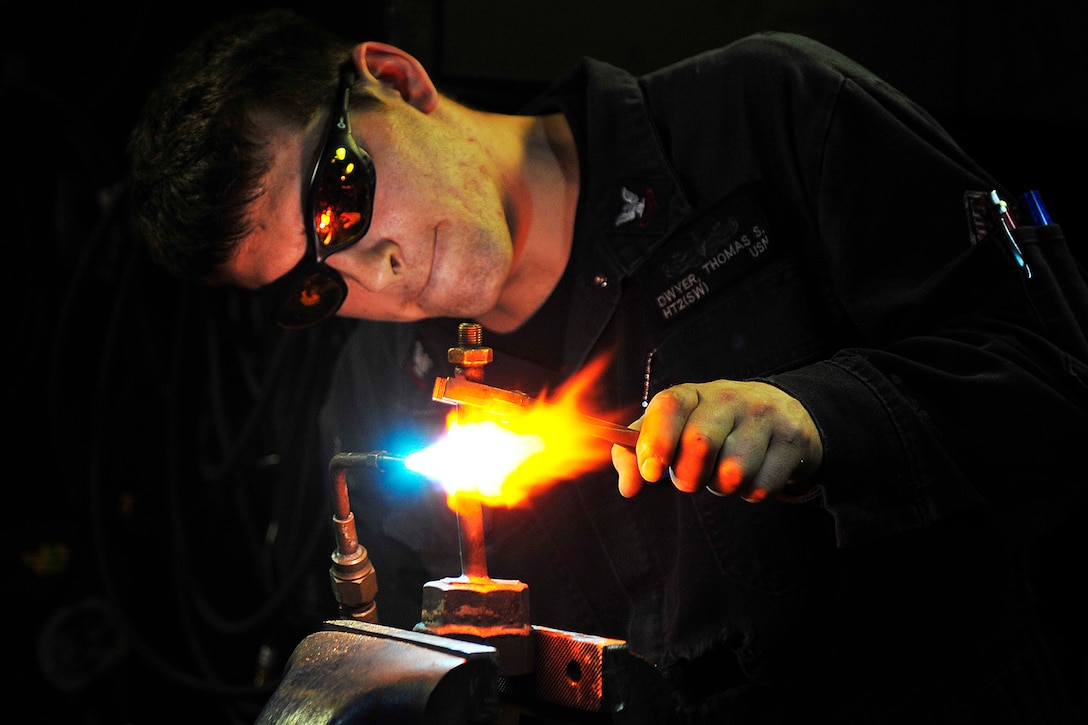 Navy Petty Officer 2nd Class Thomas Dwyer uses a torch to repair a bent bolt on the USS Blue Ridge in the Straits of Malacca, March 22, 2015. The Blue Ridge, the U.S. 7th Fleet's flagship, is patrolling in the Indo-Asia-Pacific region. Dwyer is a hull maintenance technician. Navy photo by Petty Officer 3rd Class Don Patton