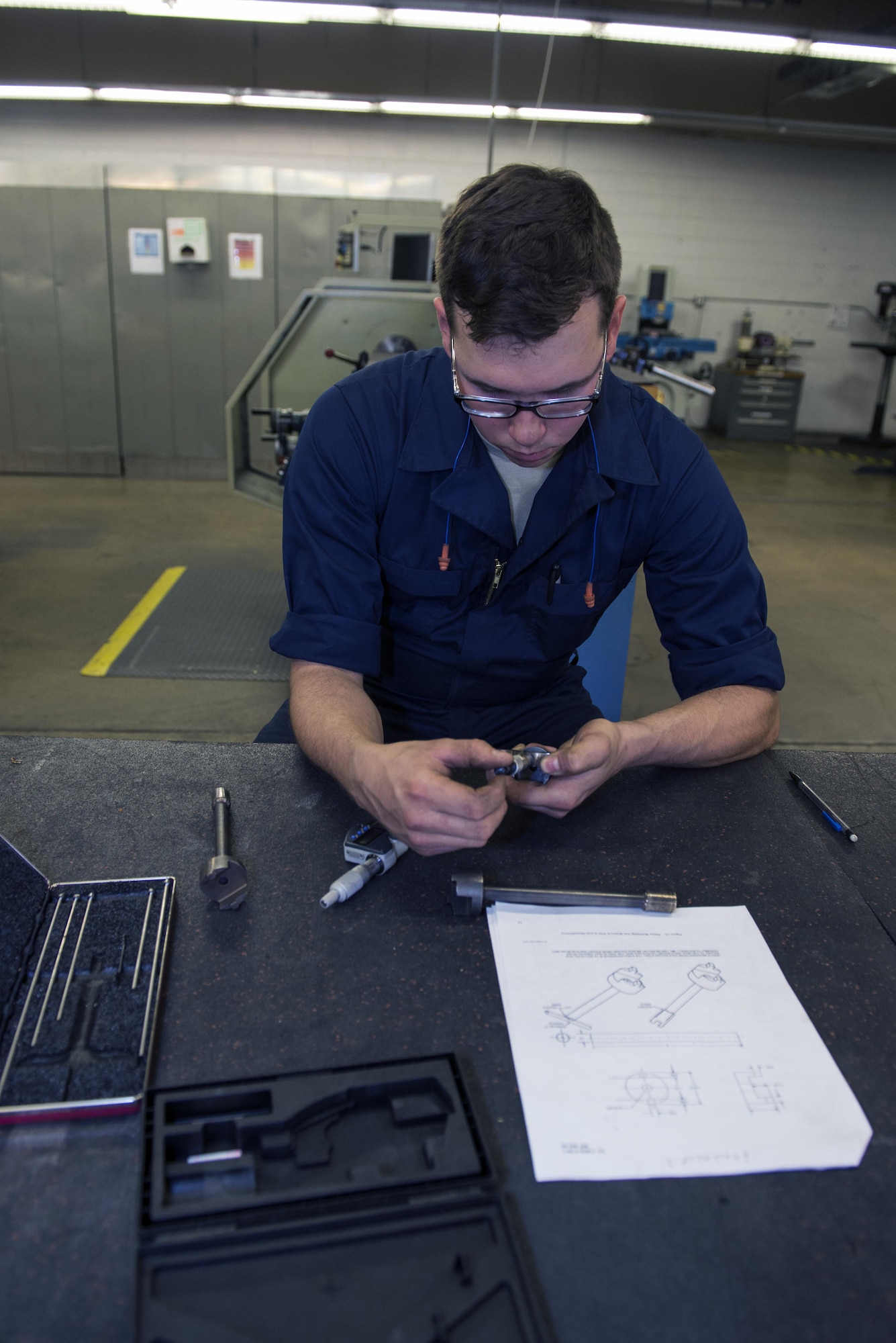 U.S. Air Force Airman 1st Class Joshua Tears-Knapp, 23d Equipment Maintenance Squadron aircraft metals technology technician, reviews a blueprint to assemble a nut removal tool with a micrometer, March 18, 2016, at Moody Air Force Base, Ga. In addition to creating aircraft and equipment components, metals technology technicians write programs for manufacturing methods, maintain and inspect metal working machinery and draw sketches and templates for select materials. (U.S. Air Force photo by Airman 1st Class Greg Nash/Released)  