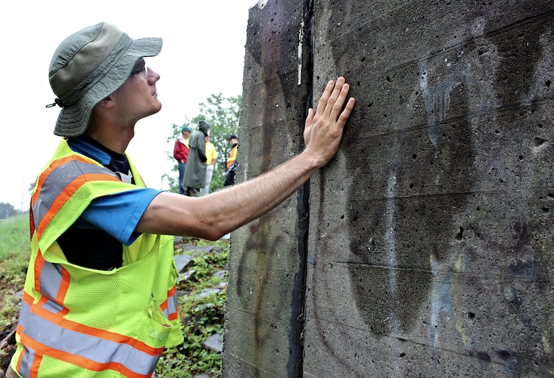 Alex Baldowski, Baltimore District civil engineer, checks for cracking in a floodwall in Johnson City, New York, July 8, 2015. The condition of floodwalls is an important part of the levee inspection checklist to determine how the levee may perform during the next flood. The levee was built by the Corps, and New York State Department of Environmental Conservation operates and maintains the levee.