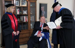 National Intelligence University President Dr. David Ellison presents an honorary degree to the Honorable George H.W. Bush in Houston, Texas on March 8, 2016.