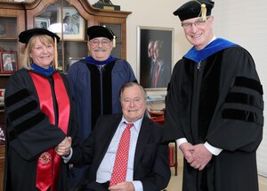The Honorable George H.W. Bush shakes hands with NIU Provost Dr. Susan Studds (left) and is joined by Dr. Don Hanle, Dean of the College of Strategic Intelligence (center), and NIU President Dr. David Ellison (right).
