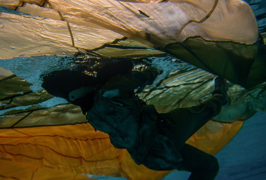 An aircrew member simulates evading a parachute canopy during a Survival, Evasion, Resistance and Escape water survival class in Shreveport, La., March 15, 2016. Aircrew practiced crucial water survival skills in a safe, controlled environment supervised by SERE specialists. The canopy has 28 lines that have the potential to entangle during the landing process.  The class provided aircrew the opportunity to experience extreme conditions and reduce the possibility of disorientation during a real world scenario. (U.S. Air Force photo/Senior Airman Mozer O. Da Cunha)