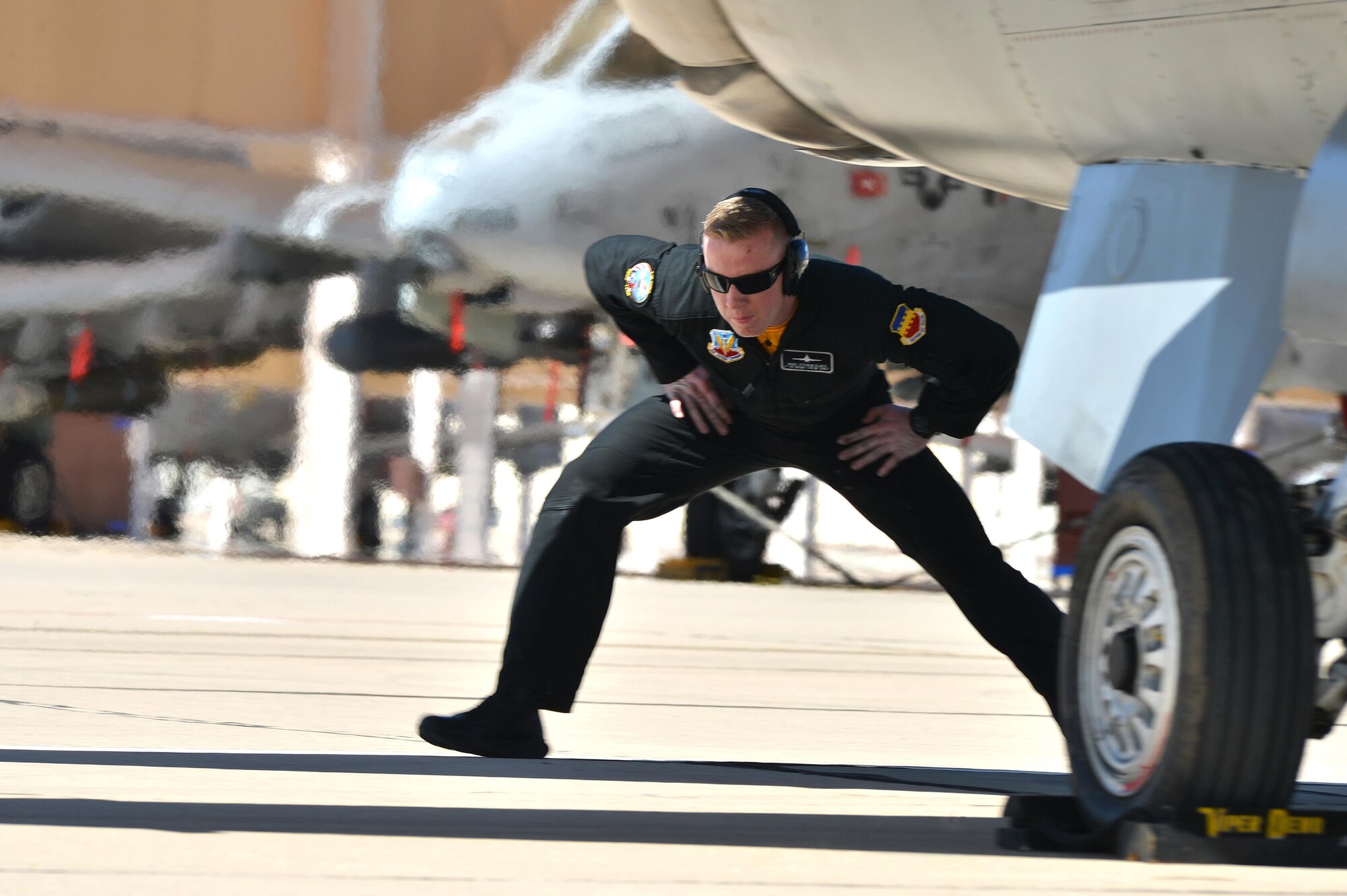 U.S. Air Force Staff Sgt. Steven Elder, F-16 Viper Demo Team crew chief, ducks under the exhaust of an F-16 Fighting Falcon during a “Comm out Demo launch” at the Heritage Flight Training Course at Davis-Monthan Air Force Base, Ariz., March 4, 2016. The Air Combat Command demo teams spent four days practicing their demonstrations with the Heritage Flight pilots. (U.S. Air Force photo by Senior Airman Diana M. Cossaboom)