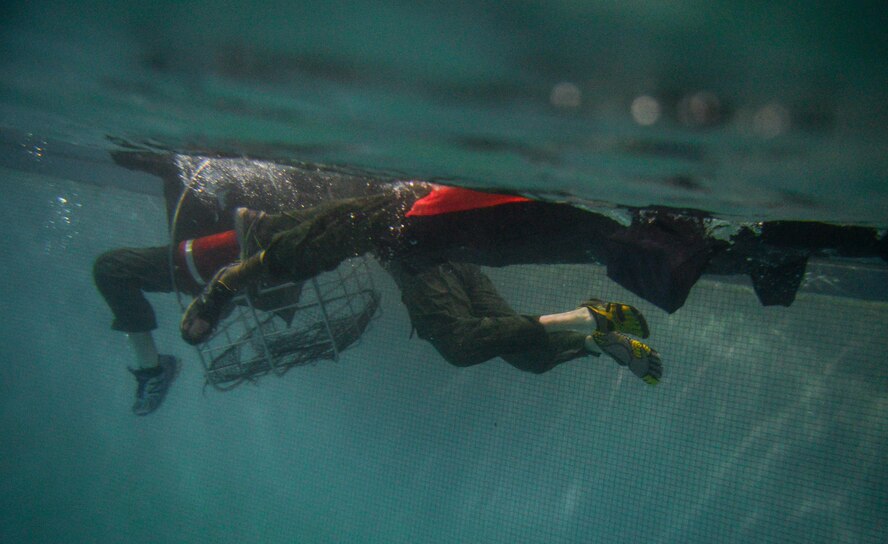 An Aircrew member enters a rescue basket during a Survival, Evasion, Resistance and Escape water survival class in Shreveport, La., March 15, 2016. Aircrew learned boarding procedures for the Coast Guard rescue baskets such as correct harness anchor points and hand signals used in a real-world scenario. (U.S. Air Force photo/Senior Airman Mozer O. Da Cunha)