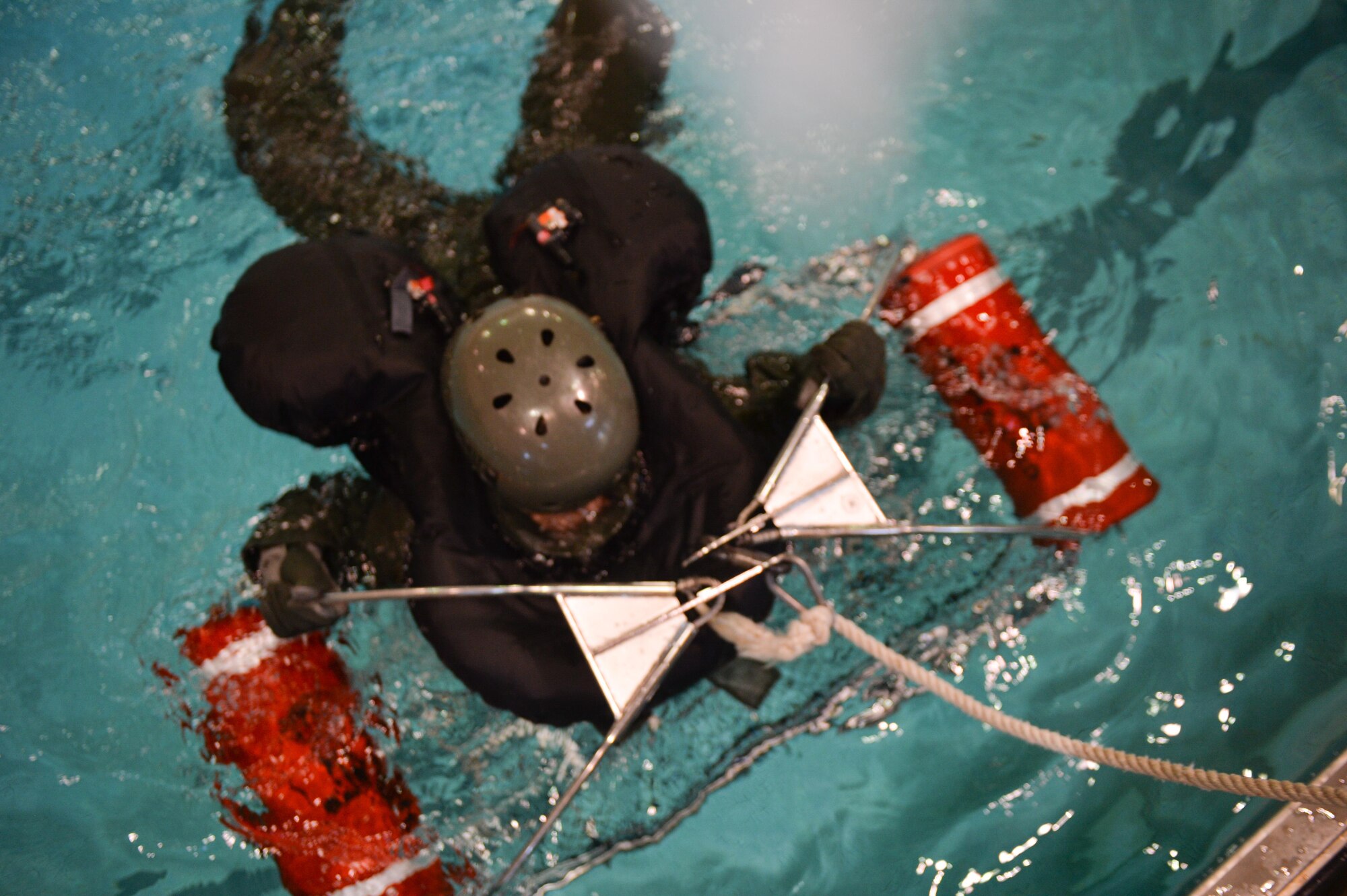 An Airman assigned to Barksdale Air Force Base, La., prepares for a simulated rescue basket extraction during a Survival, Evasion, Resistance and Escape water survival class in Shreveport, La., March 15, 2016. U.S. Coast Guard helicopters use rescue baskets as a primary extraction tool. Aircrew practiced correct grounding techniques used to avoid static electricity and rescue basket boarding techniques. (U.S. Air Force photo/Senior Airman Mozer O. Da Cunha)