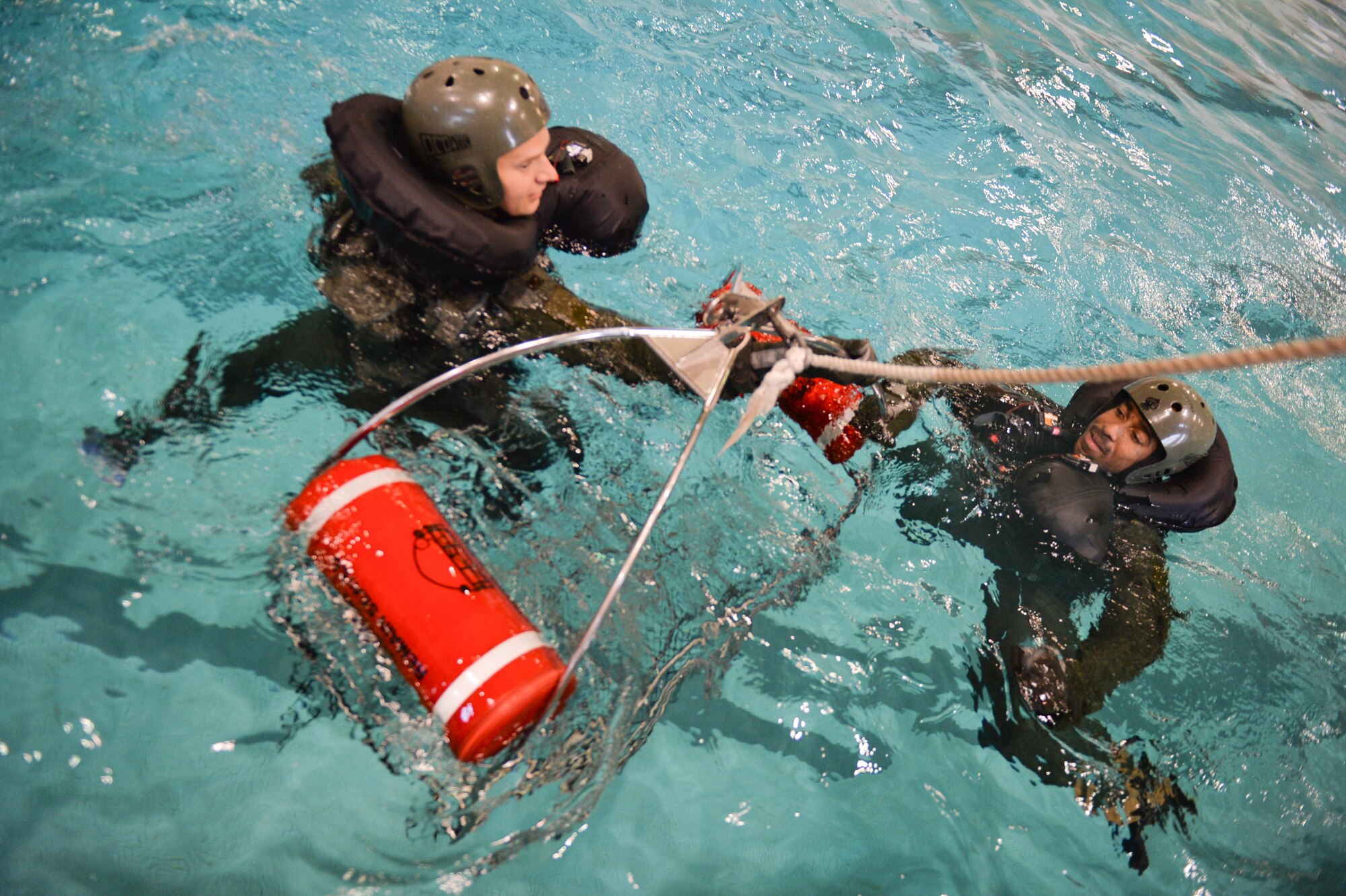 Aircrew members approach a rescue basket during a Survival, Evasion, Resistance and Escape water survival class in Shreveport, La., March 15, 2016. Aircrew practiced proper grounding procedures making sure the rescue basket was safe and free of static electricity prior to approaching the device. (U.S. Air Force photo/Senior Airman Mozer O. Da Cunha)