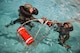 Aircrew members approach a rescue basket during a Survival, Evasion, Resistance and Escape water survival class in Shreveport, La., March 15, 2016. Aircrew practiced proper grounding procedures making sure the rescue basket was safe and free of static electricity prior to approaching the device. (U.S. Air Force photo/Senior Airman Mozer O. Da Cunha)